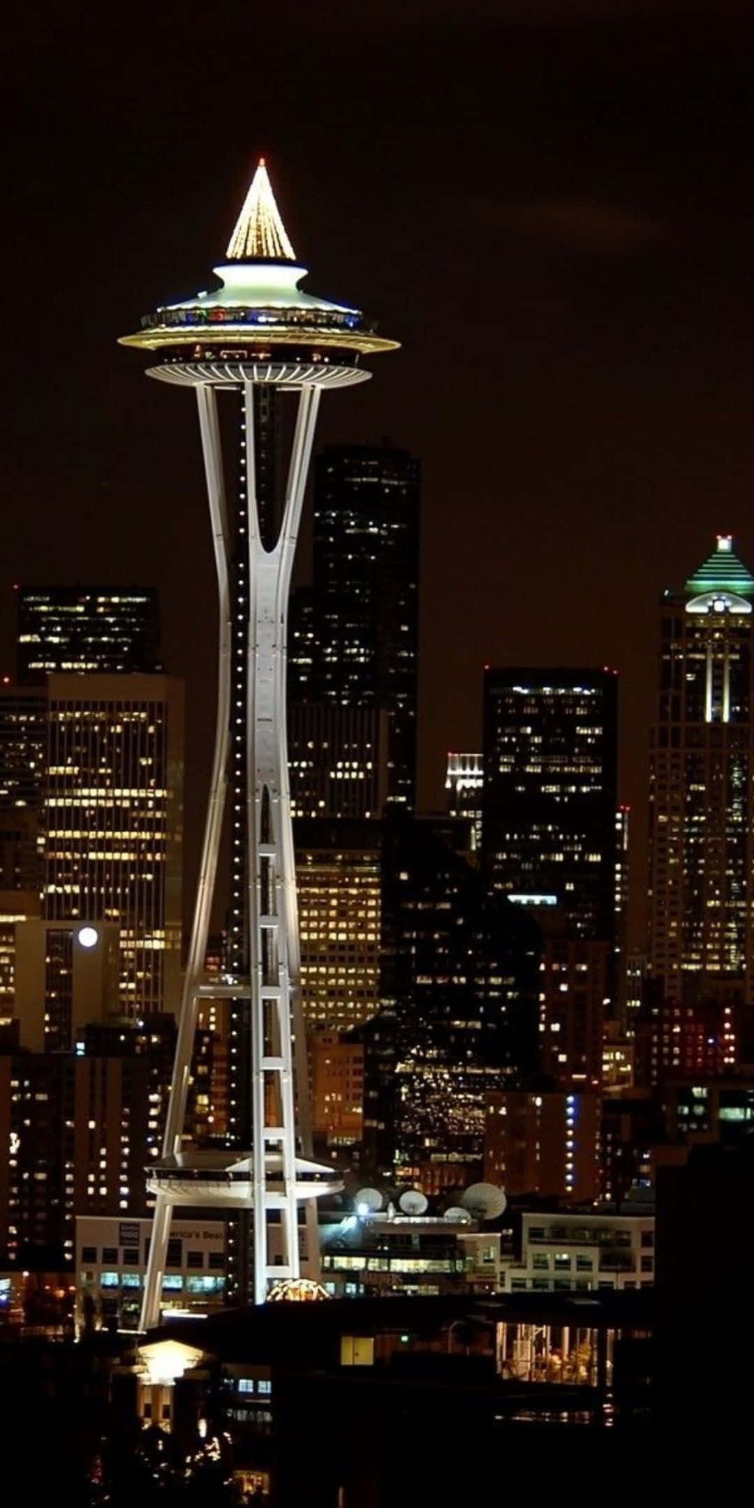 Pixel 3 Seattle 桌布 壁紙 — 發光的太空針塔在黑暗的天空中高高聳立，被西雅圖充滿活力的夜景中閃爍的摩天大樓所環繞。