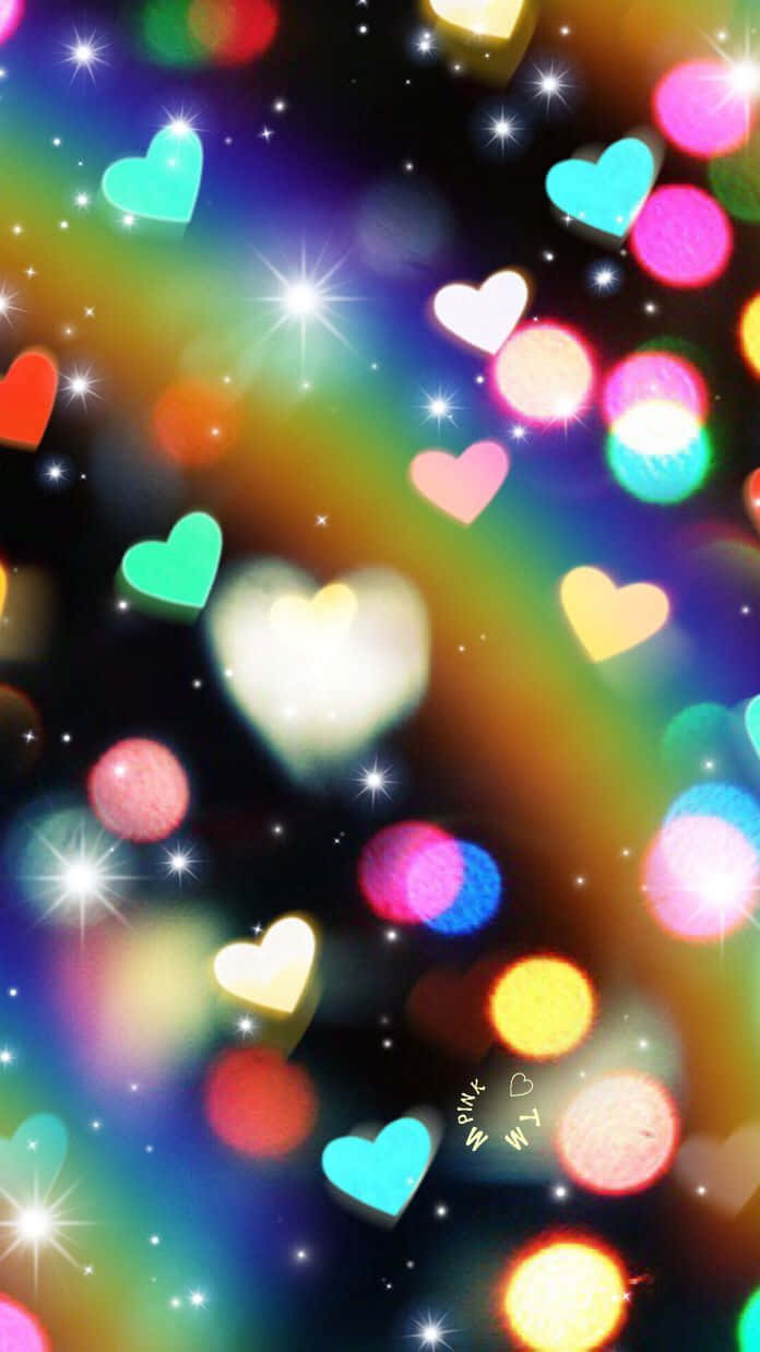Rainbow Heart 桌布 壁紙 — 發光的心形和星爆在彩虹漸變背景上漂浮，帶有散景燈光。