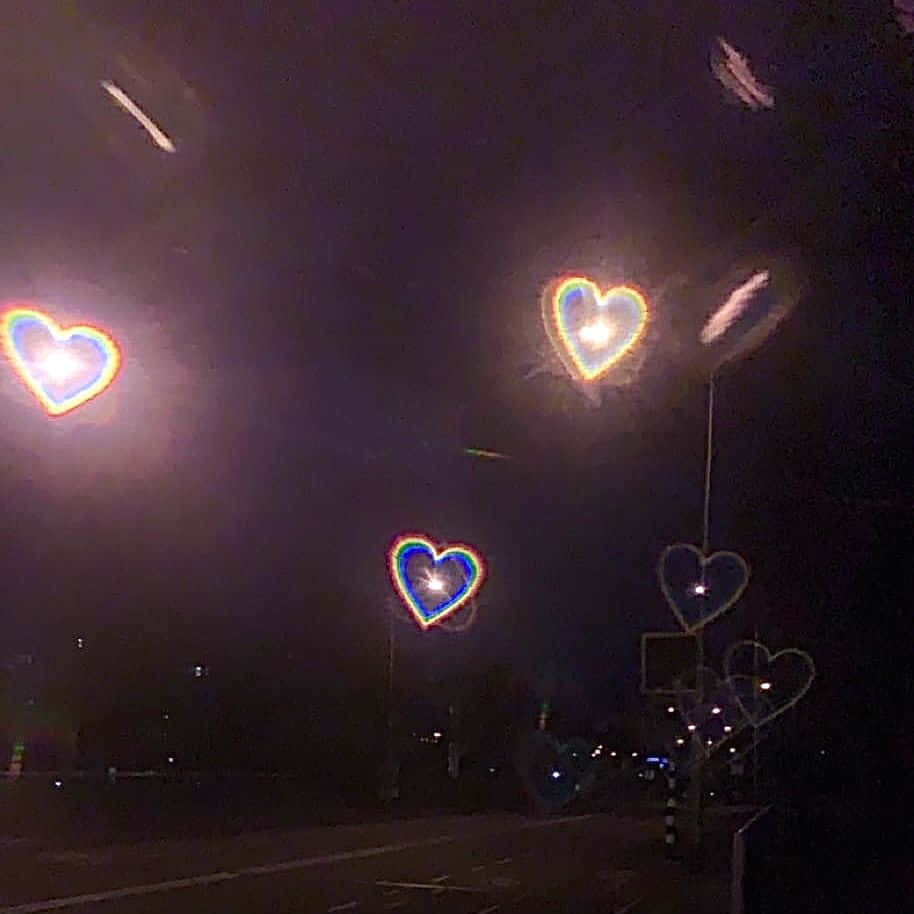 Heart Shape 桌布 壁紙 — 發光的愛心形燈光在黑暗的夜空中漂浮在寧靜的路邊場景上方。