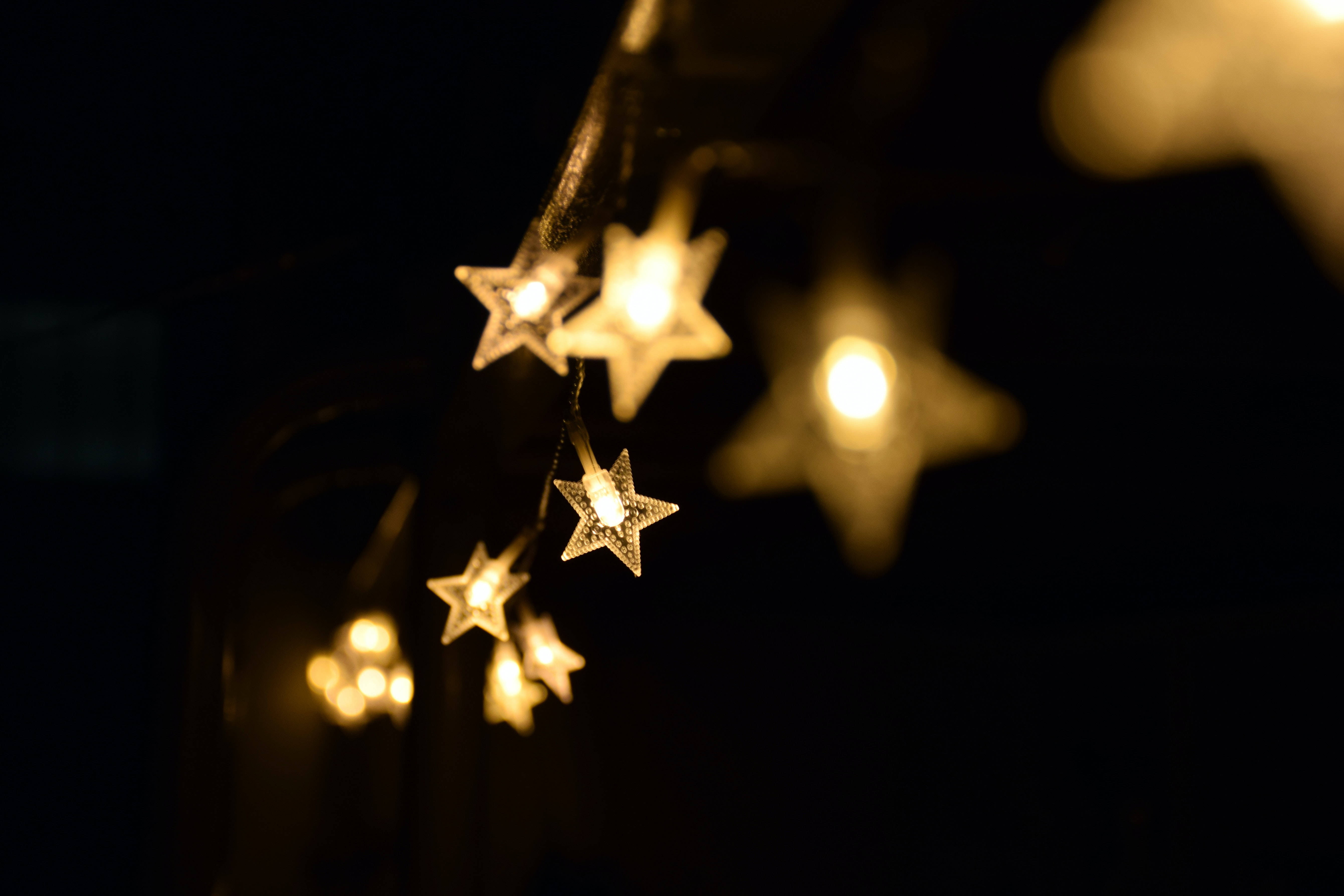 Stars 桌布 壁紙 — 發光的星形仙女燈柔和地懸掛在黑暗背景上，營造出溫暖神奇的氛圍。