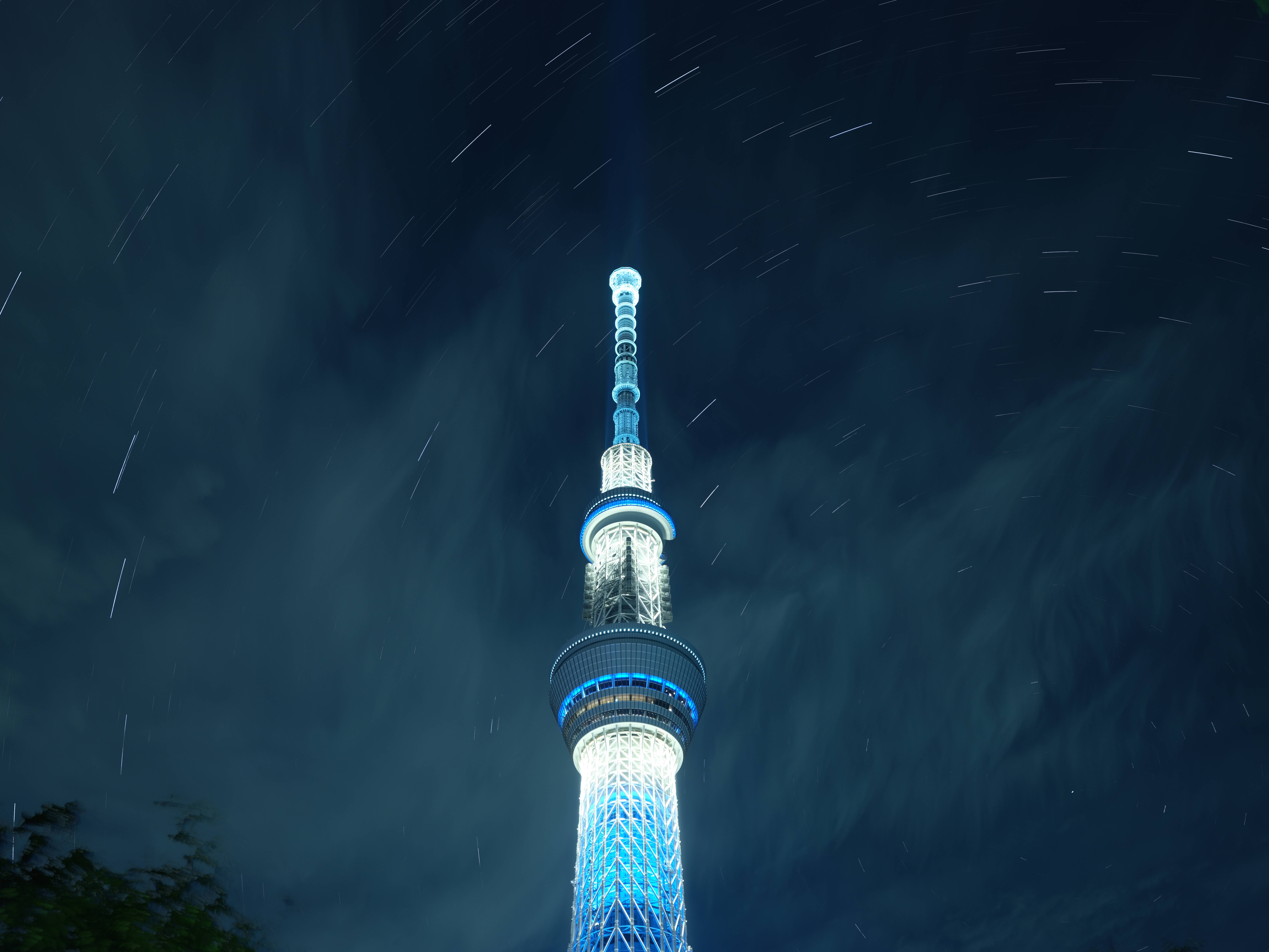 東京 桌布 壁紙 — 發光的東京晴空塔刺穿星空，光跡圍繞其照明結構旋轉。