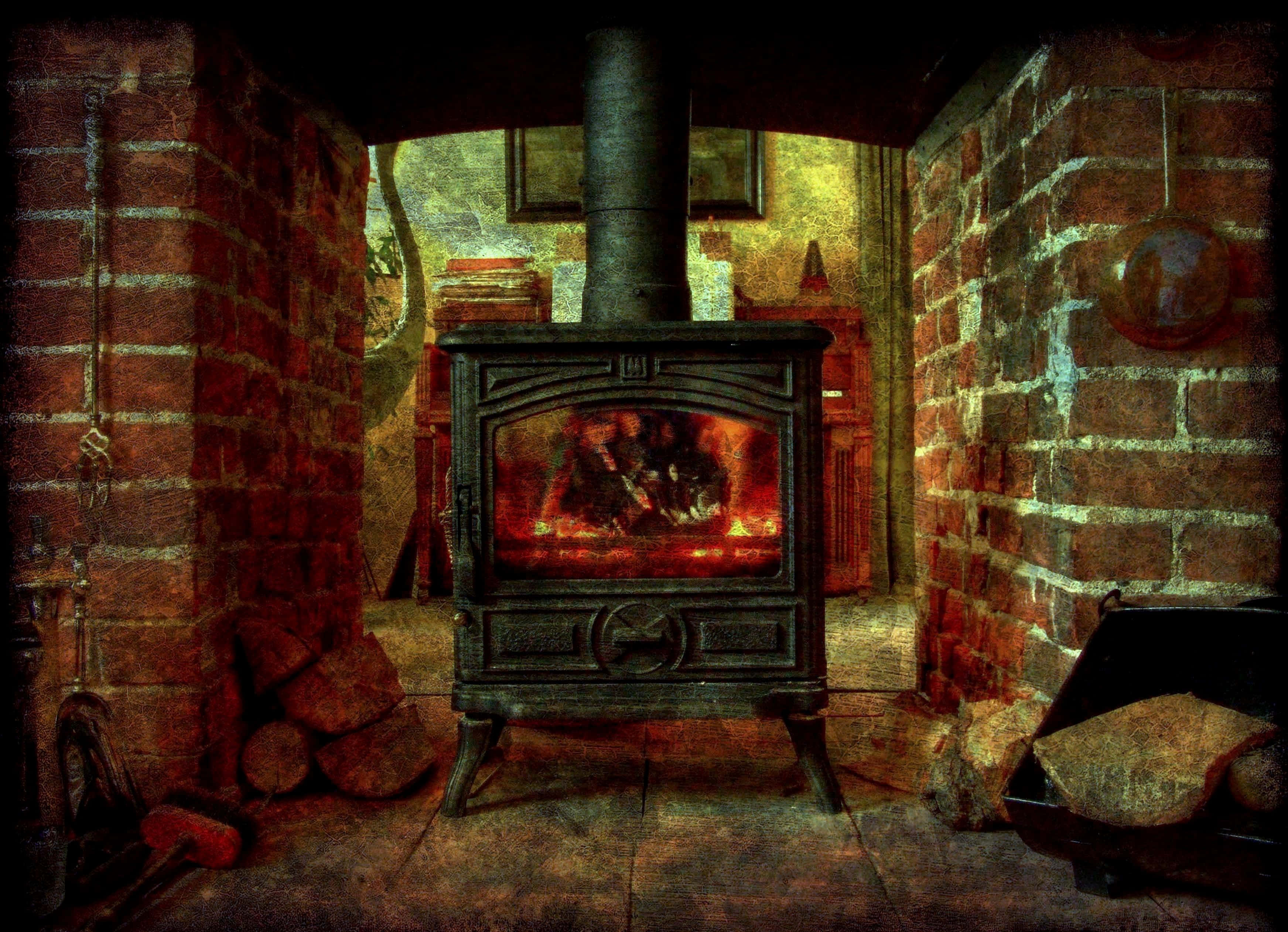 Cozy Fire 桌布 壁紙 — 發光的柴火爐在質樸的磚牆房間中散發溫暖，房間內有堆疊的木柴和復古裝飾。