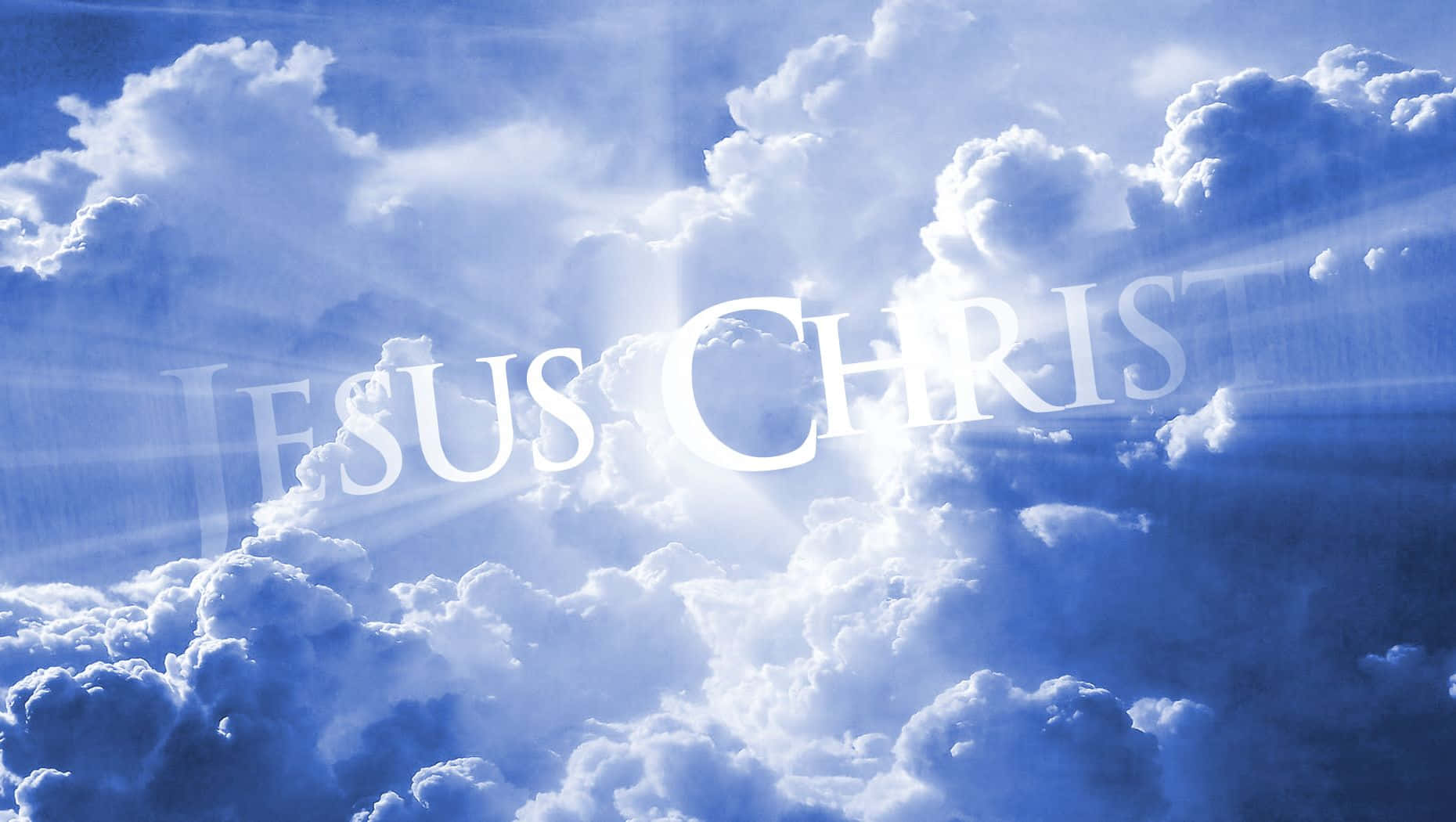 Typography 桌布 壁紙 — 發光的白色文字「JESUS CHRIST」穿過蓬鬆的雲層，在明亮的藍天中閃耀，伴隨著神聖的光束。