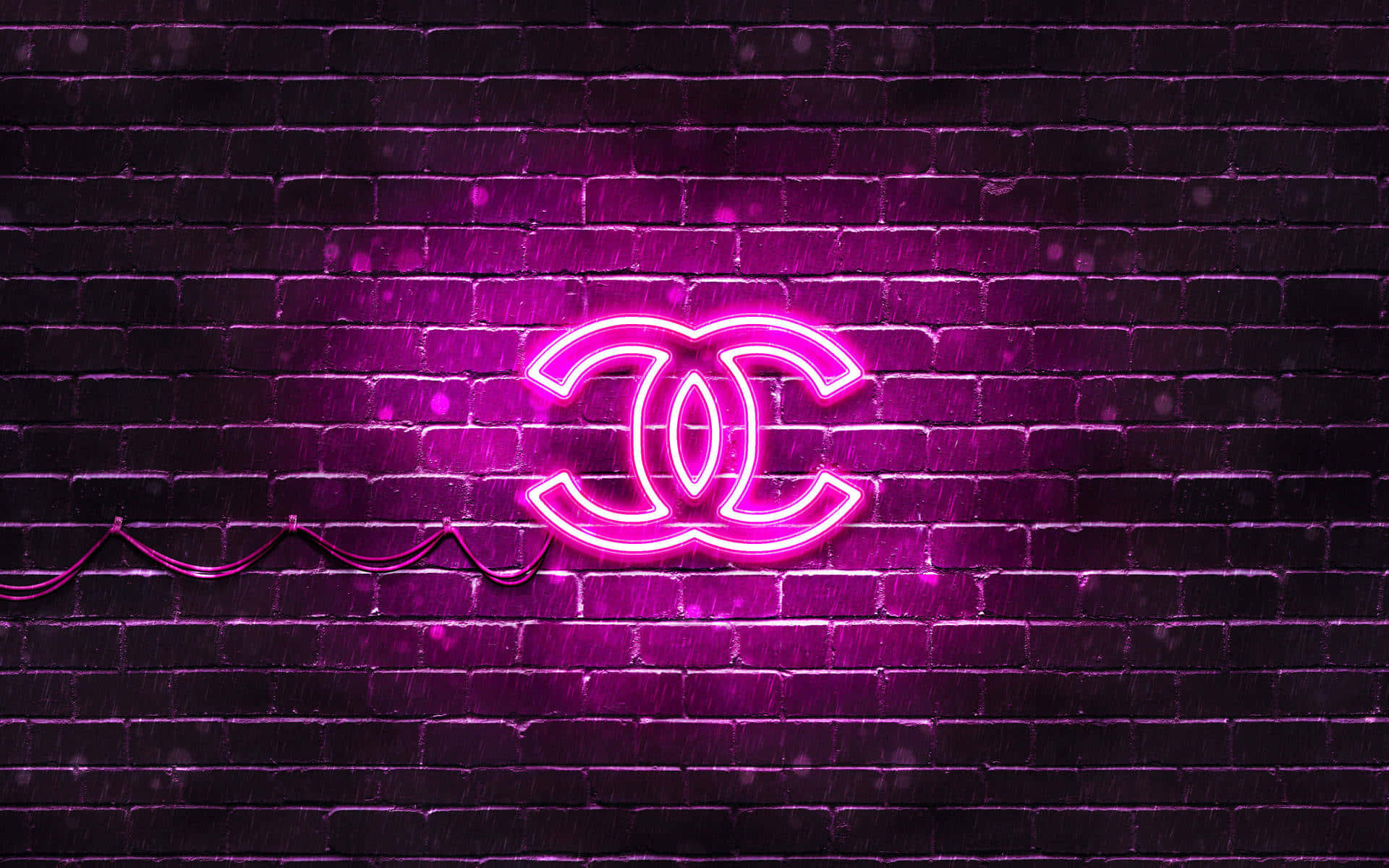 Chanel 桌布 壁紙 — 發光的粉紅色霓虹燈 Chanel 標誌在雨夜條件下照亮了潮濕的深色磚牆。