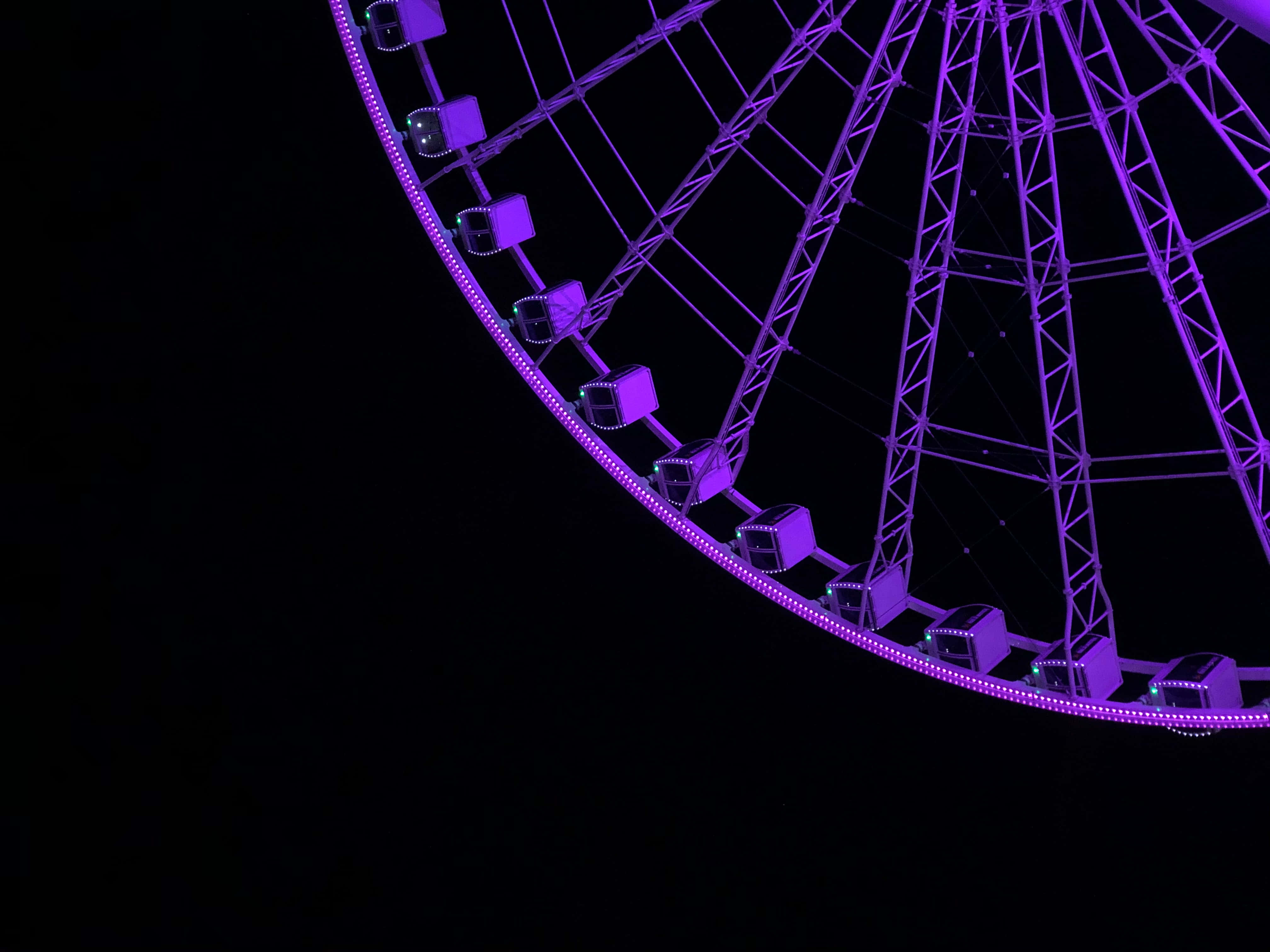 Dark Purple 桌布 壁紙 — 發光的紫色摩天輪在漆黑的夜空中脫穎而出，構成引人注目的城市夜景。