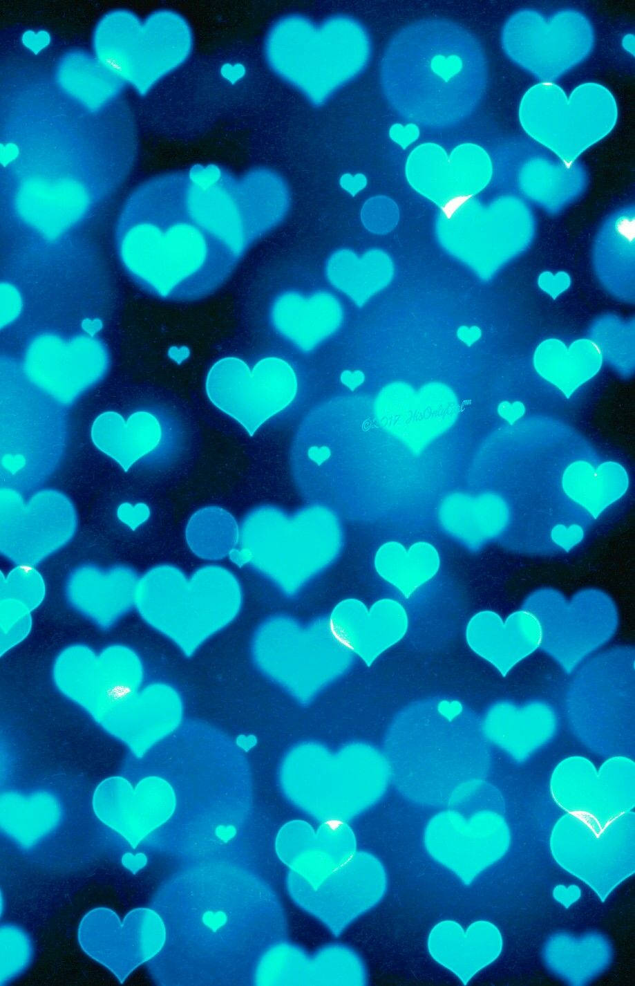 Blue Heart 桌布 壁紙 — 發光的綠松色心形在夢幻的藍色散景背景中漂浮，帶有柔和的光折射。