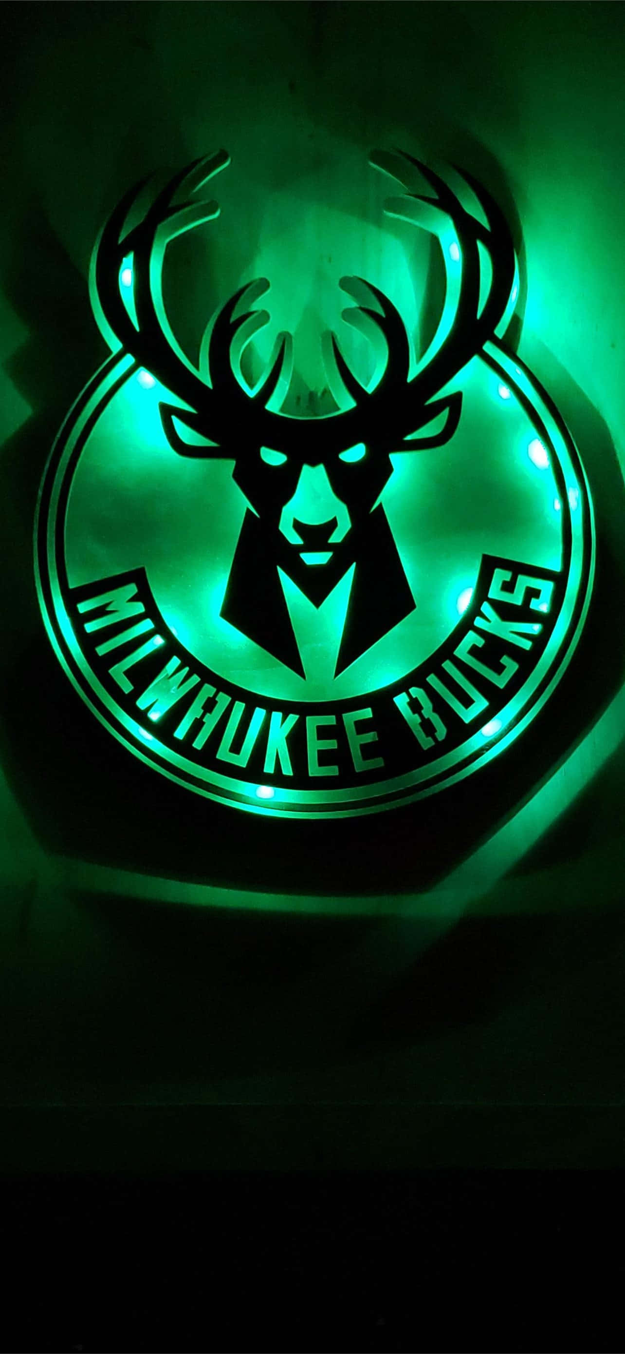 Milwaukee Bucks Logo 桌布 壁紙 — 發光的綠色密爾瓦基公鹿標誌燈照亮了一個黑暗的房間，帶有鹿頭和鹿角的設計。