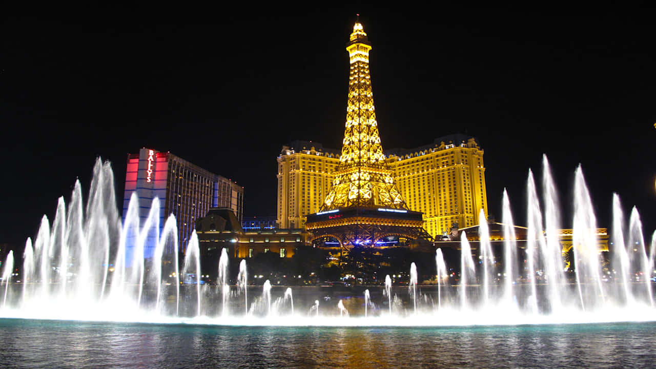 720p Las Vegas 桌布 壁紙 — 發光的艾菲爾鐵塔複製品和噴泉在拉斯維加斯的夜空中閃耀，充滿活力的燈光倒映在水面上。