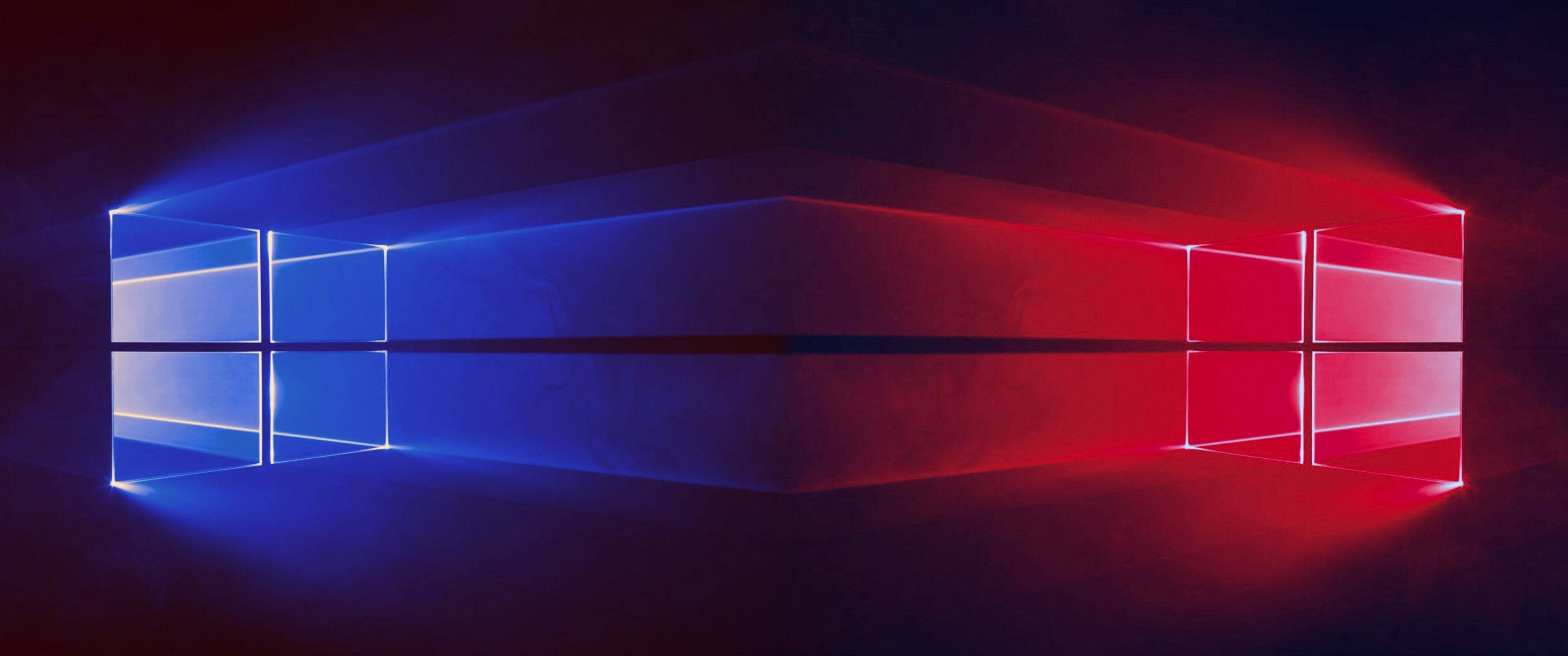 Windows 10 桌布 壁紙 — 發光的藍色和紅色Windows標誌在帶有玻璃反射表面的深色背景上散發光芒。