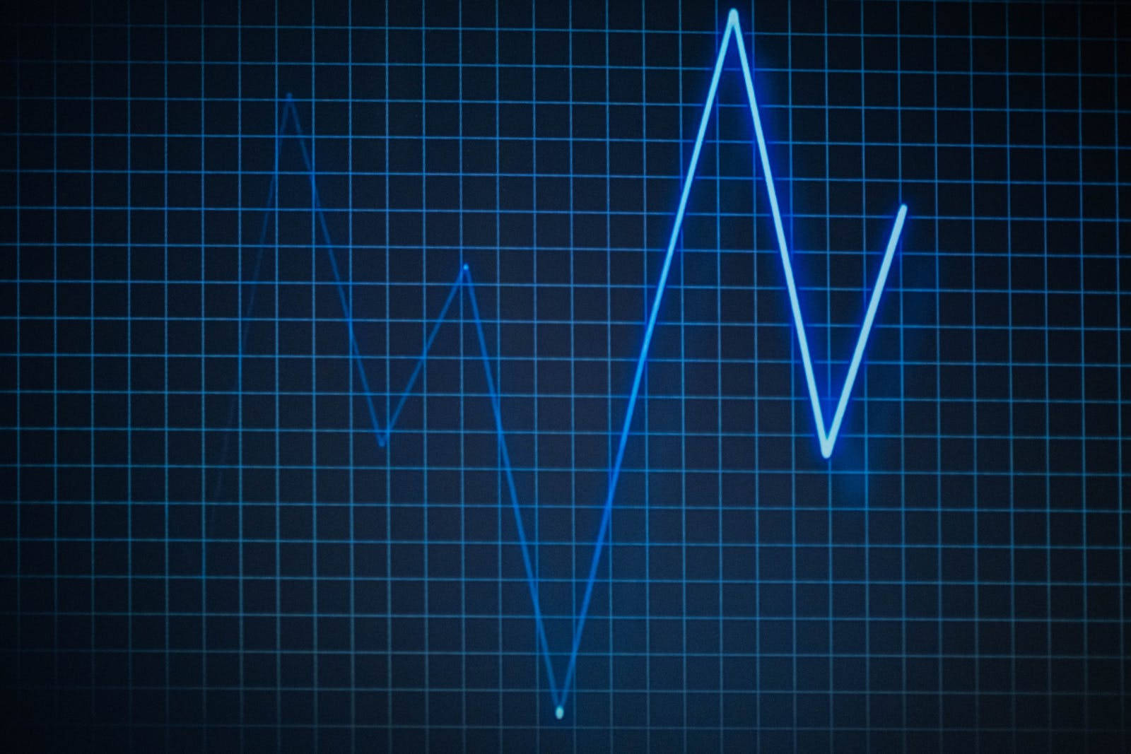 Heartbeat 桌布 壁紙 — 發光的藍色心電圖線條在深色網格背景上有節奏地脈動。