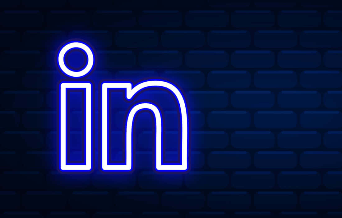 Linkedin Logo 桌布 壁紙 — 發光的藍色霓虹燈LinkedIn標誌在深色磚牆背景下明亮閃耀。