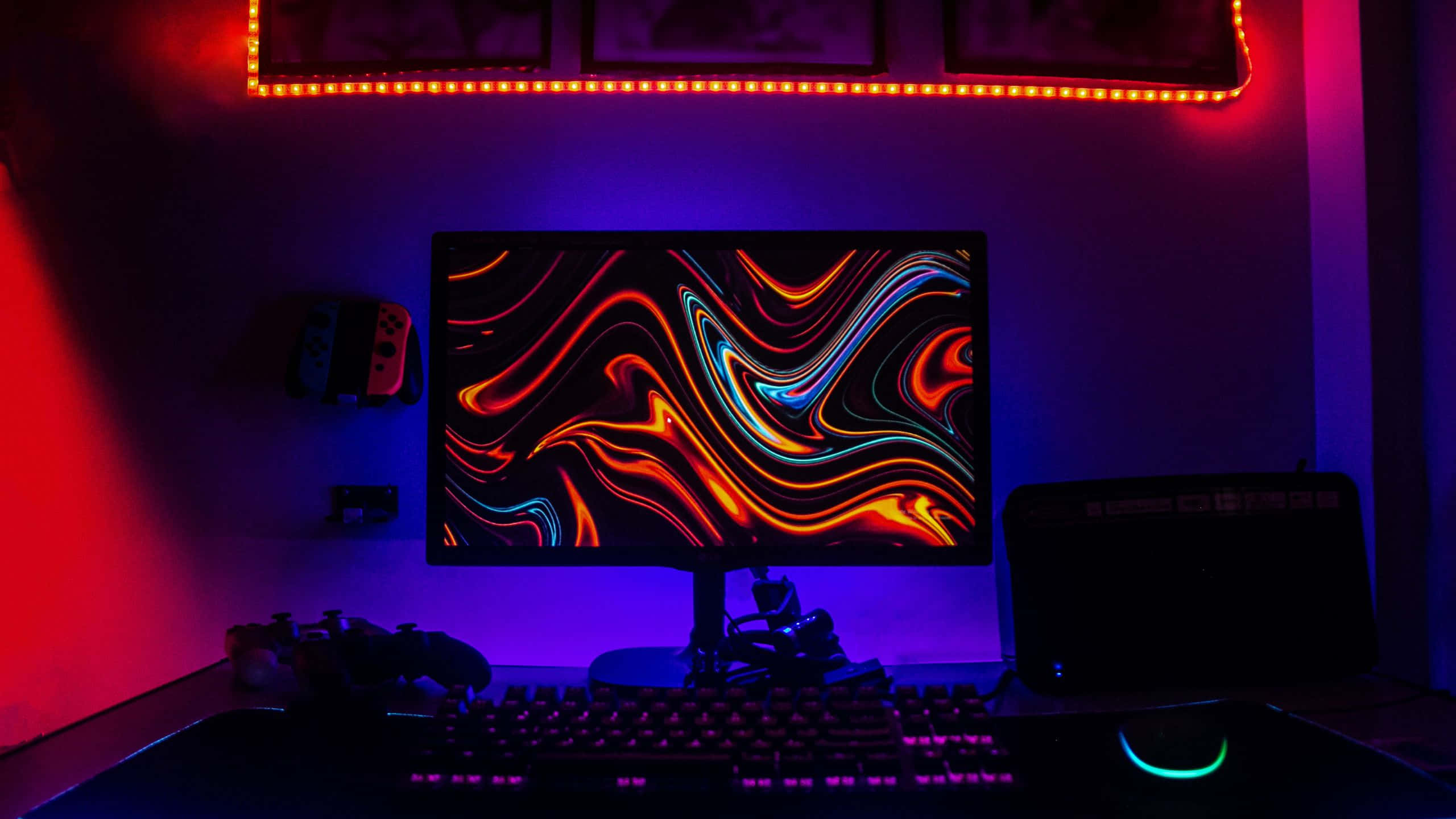Gaming Banner 桌布 壁紙 — 發光的電腦顯示器顯示鮮豔的旋轉抽象圖案，而紅色和藍色LED燈照亮了遊戲設置。