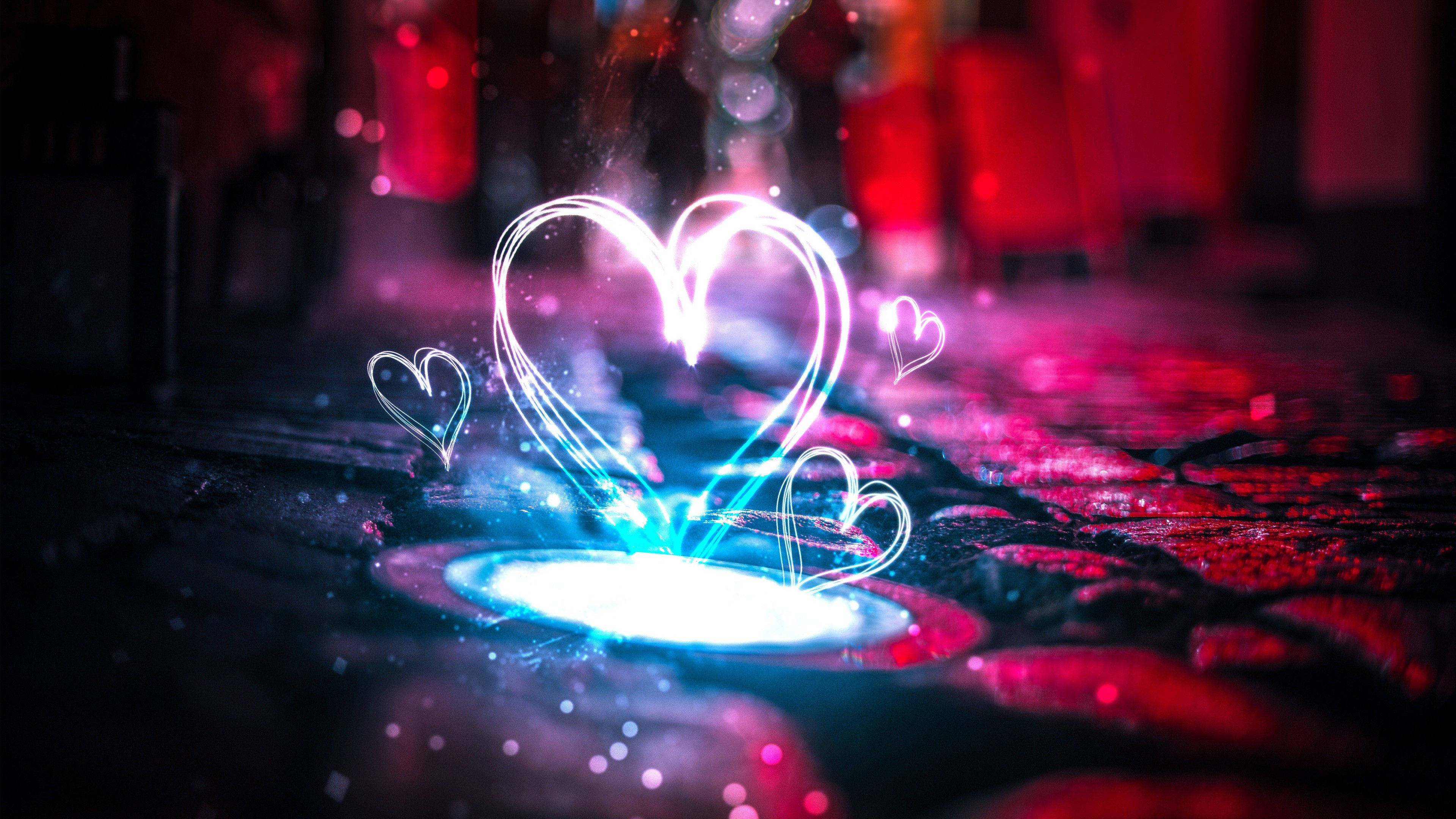 Really Cool Love 桌布 壁紙 — 發光的霓虹心形在潮濕的路面上方飄浮，背景是鮮豔的紅色和藍色燈光，帶有散景效果。