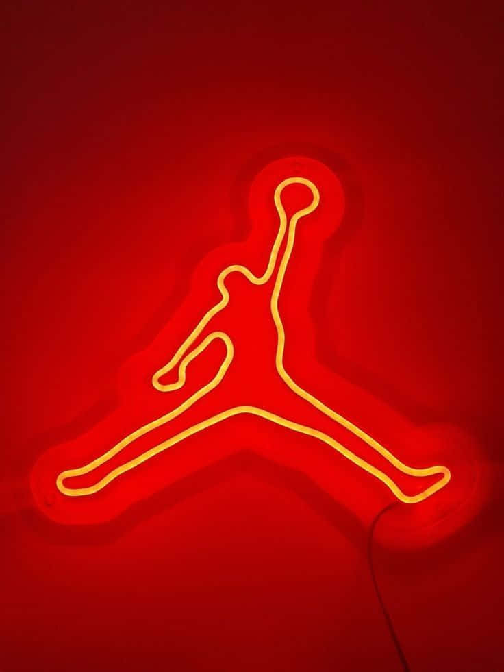 LED 桌布 壁紙 — 發光的黃色霓虹Jordan Jumpman標誌在深紅色牆壁上投射出溫暖的光芒。
