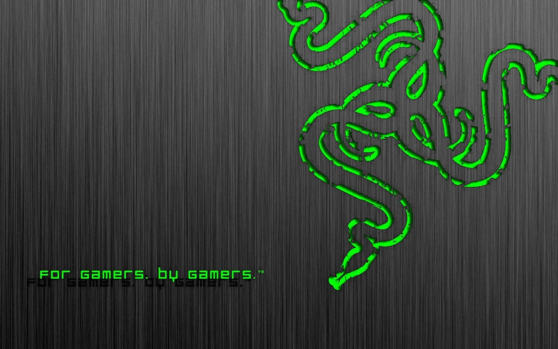 雷蛇電腦 桌布 壁紙 — 發光綠色Razer標誌蜿蜒在拉絲金屬紋理上，並以匹配的綠色顯示「for gamers by gamers」標語。