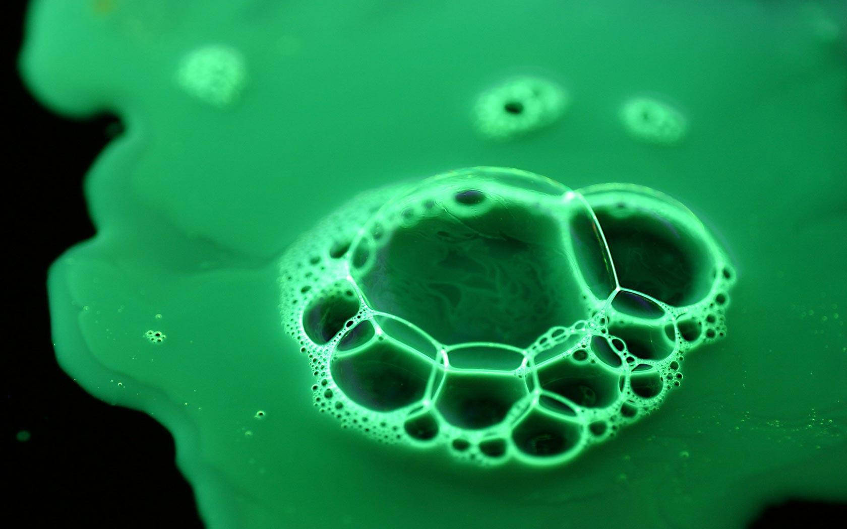 Bubbles 桌布 壁紙 — 發光綠色肥皂泡的特寫，在深色背景上形成複雜的六邊形圖案。
