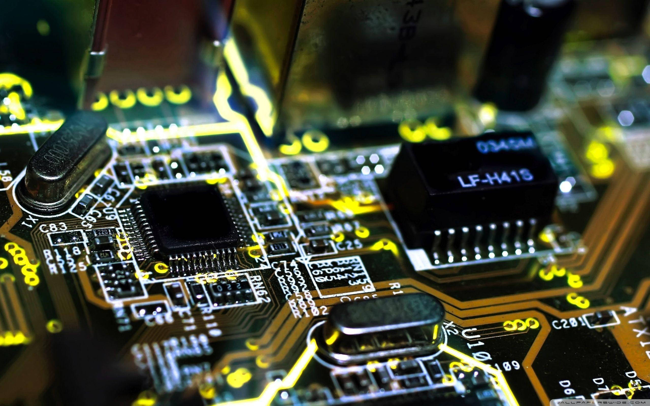 Motherboard 桌布 壁紙 — 發光黃色電路板的特寫，帶有複雜的路徑和標籤的電子元件。