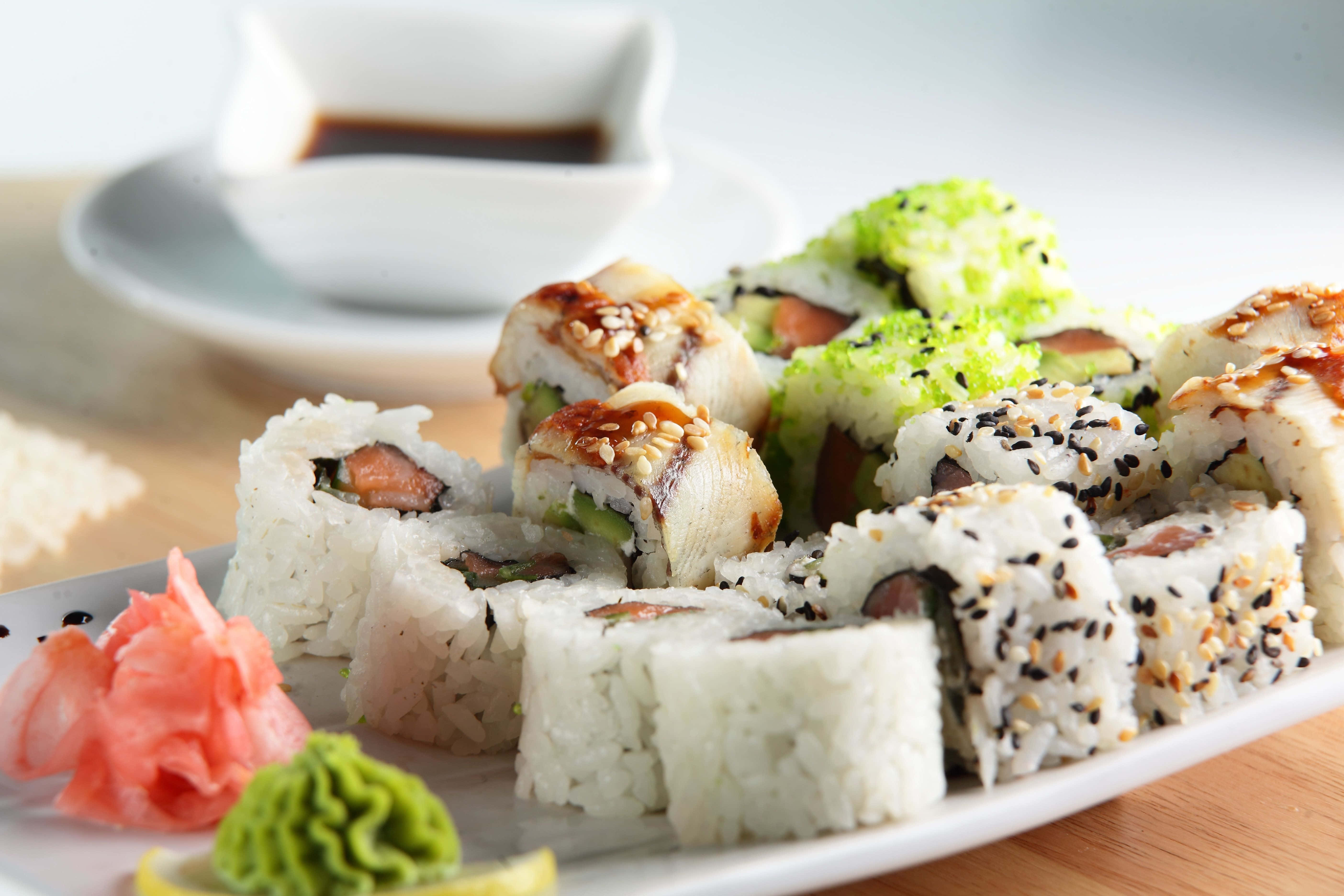 Sushi 桌布 壁紙 — 白盤上各式壽司卷的特寫，搭配芝麻、薑、Wasabi和醬油。