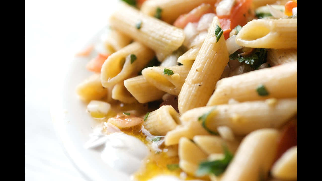 720p Pasta 桌布 壁紙 — 白盤上的筆管麵混合新鮮香草、番茄和奶油醬汁的特寫。