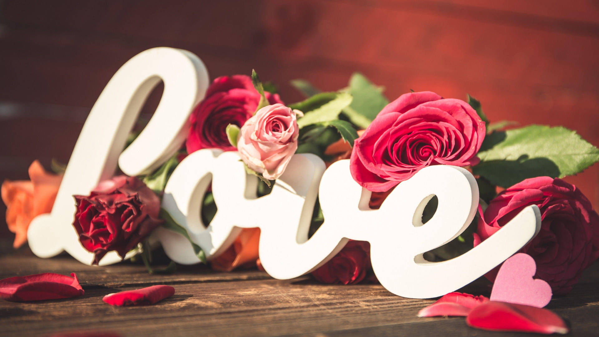 Pink Rose 桌布 壁紙 — 白色 'love' 字母點綴在鮮豔的紅粉玫瑰之間，置於質樸的木質表面上。