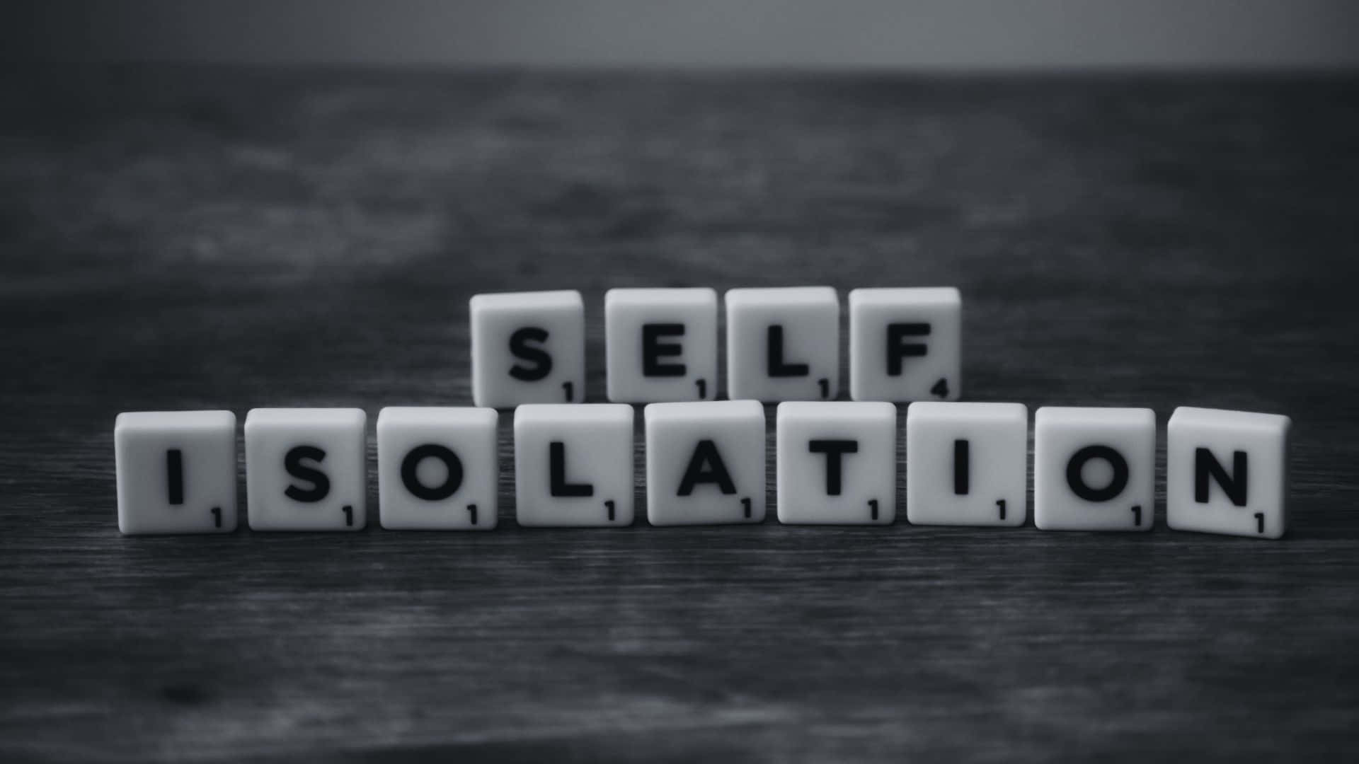 Black And White Word 桌布 壁紙 — 白色 Scrabble 字母塊拼出「自我隔離」，放在深色木質表面上，呈單色調。