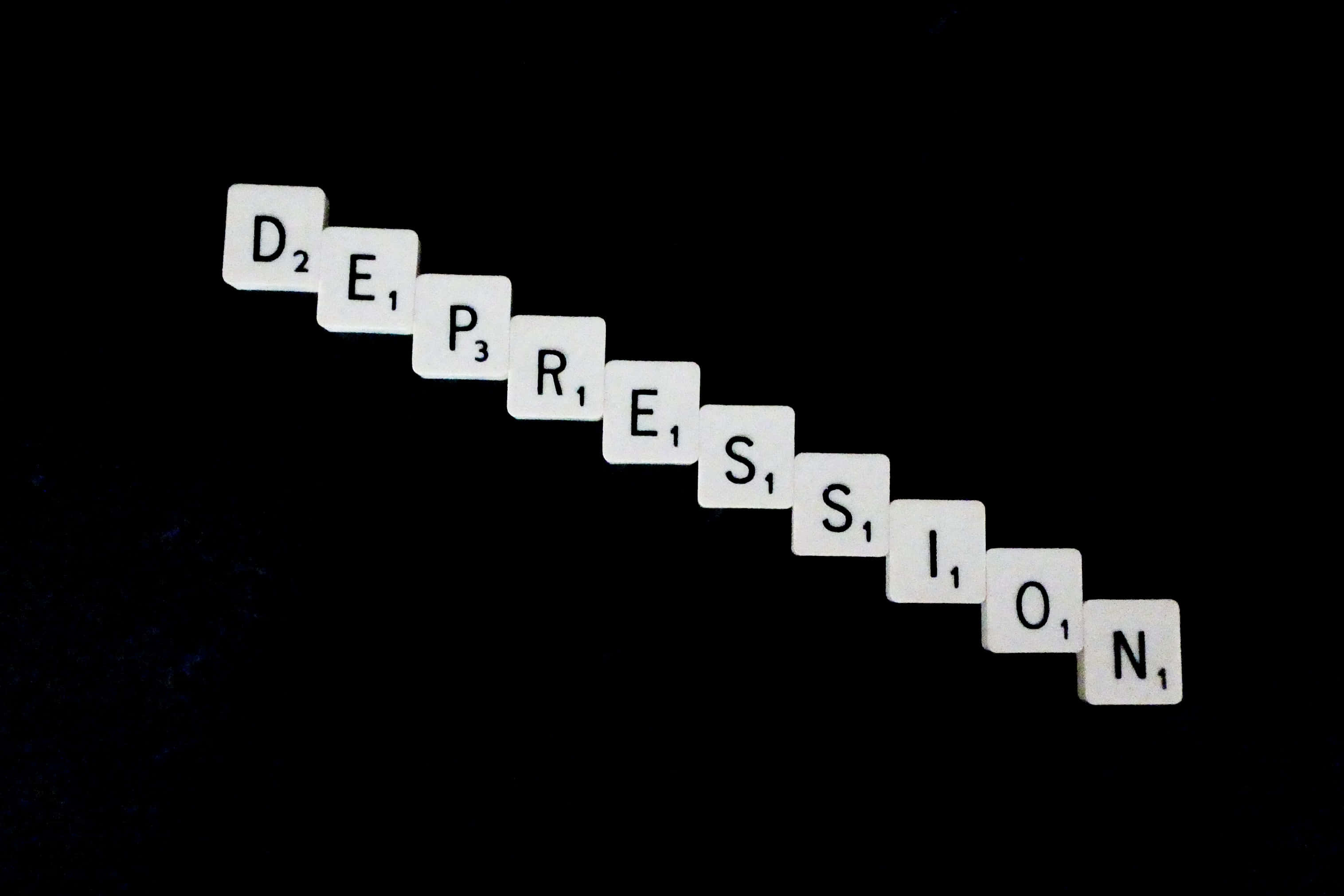 憂鬱 桌布 壁紙 — 白色 Scrabble 字母磚在純黑背景上斜向拼出 depression 一詞。