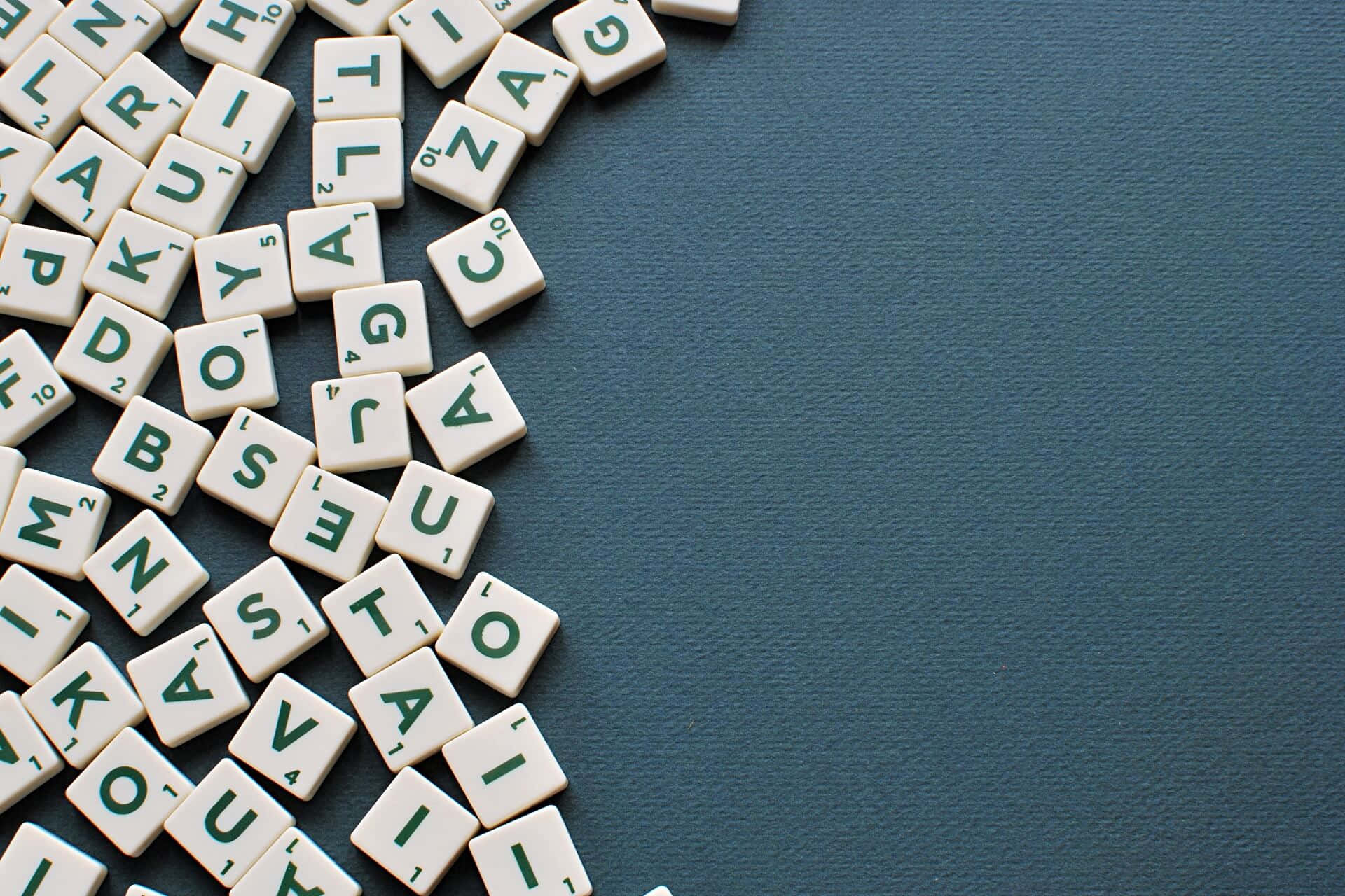 Word 桌布 壁紙 — 白色 Scrabble 瓷磚，帶有綠色字母，對角散落在有紋理的青綠色表面上。