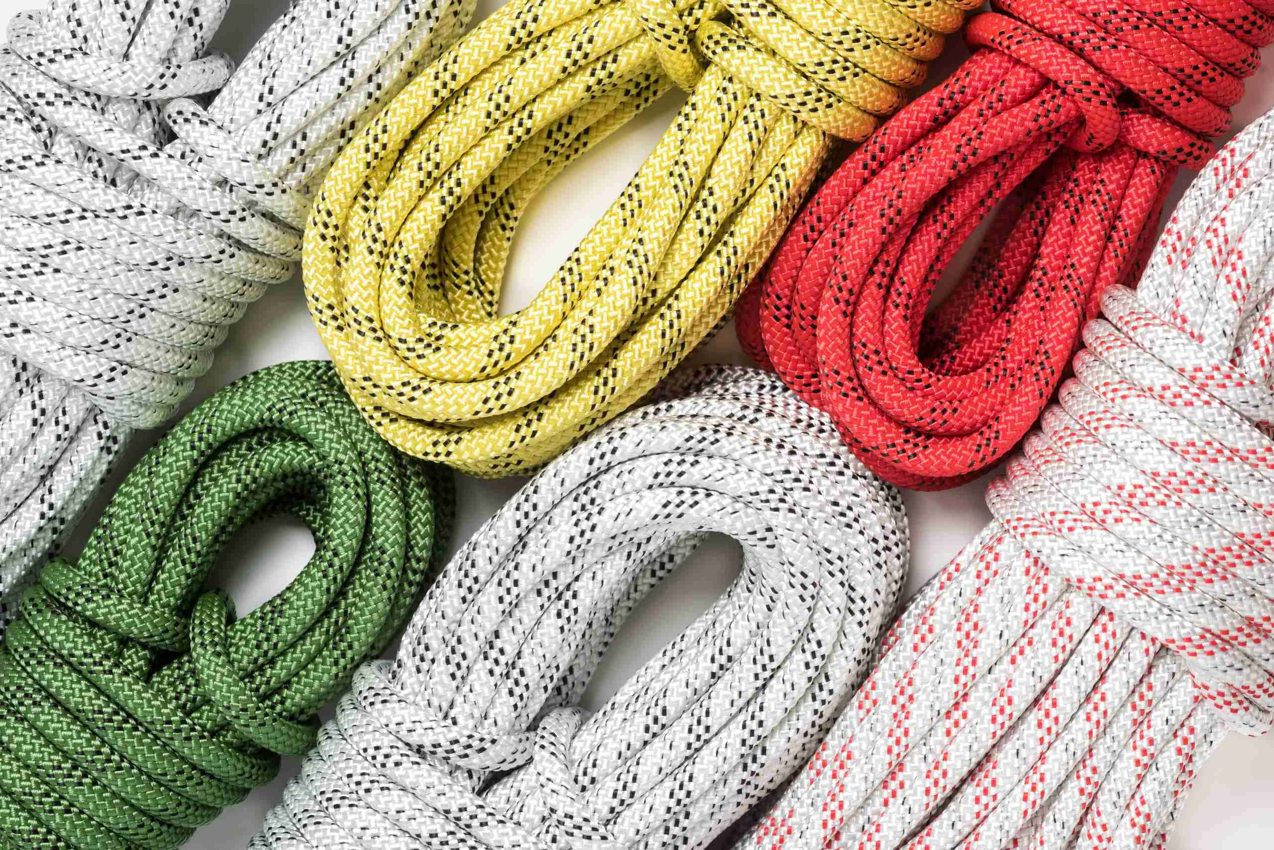rope 桌布 壁紙 — 白色、黃色、紅色、綠色和灰色的纏繞繩索，帶有黑色或紅色斑點，排列成色彩繽紛的圖案。