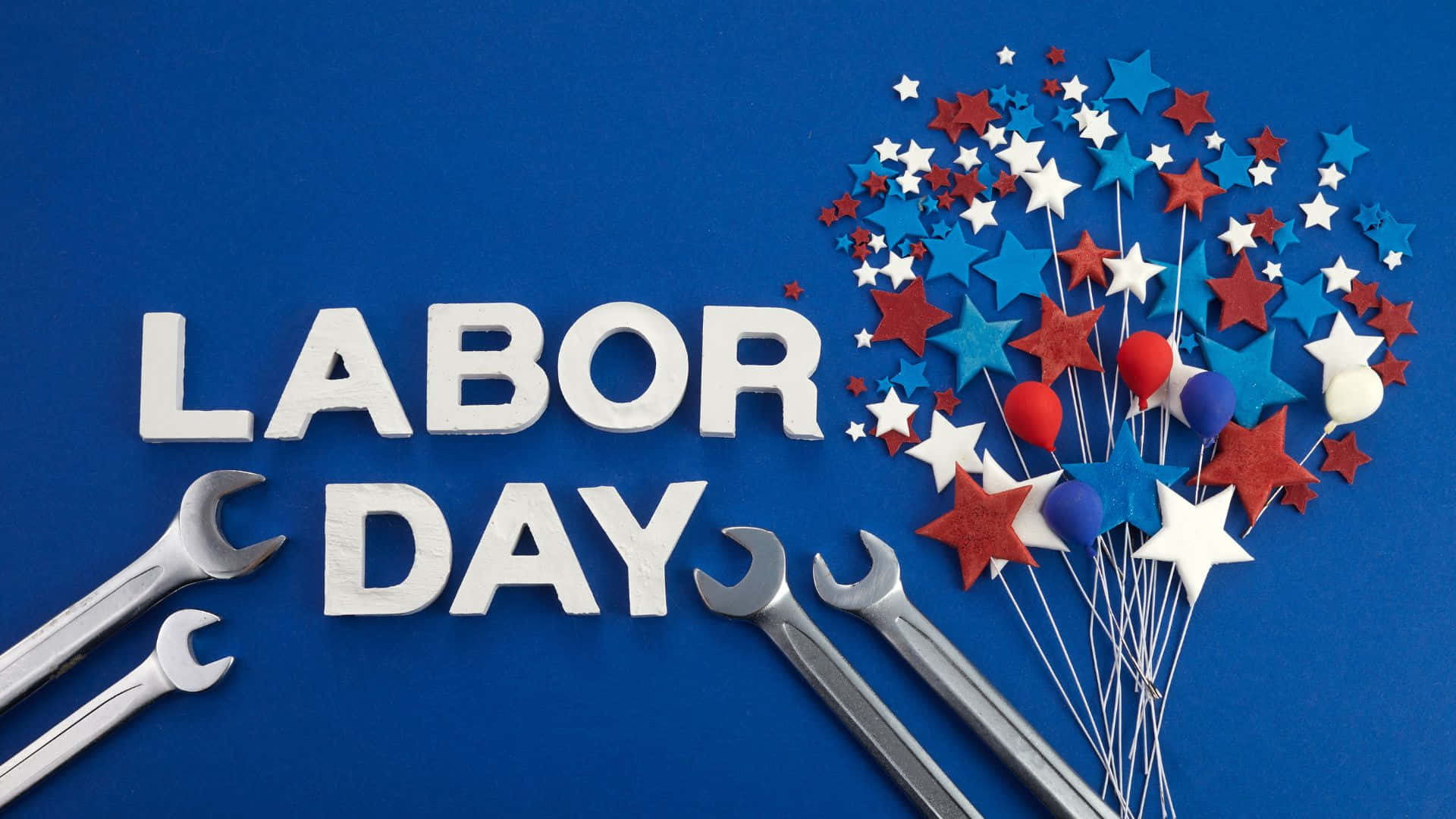 勞動節 桌布 壁紙 — 白色3D字母拼出LABOR DAY，放置在藍色背景上，旁邊有銀色扳手和紅白藍星形氣球。