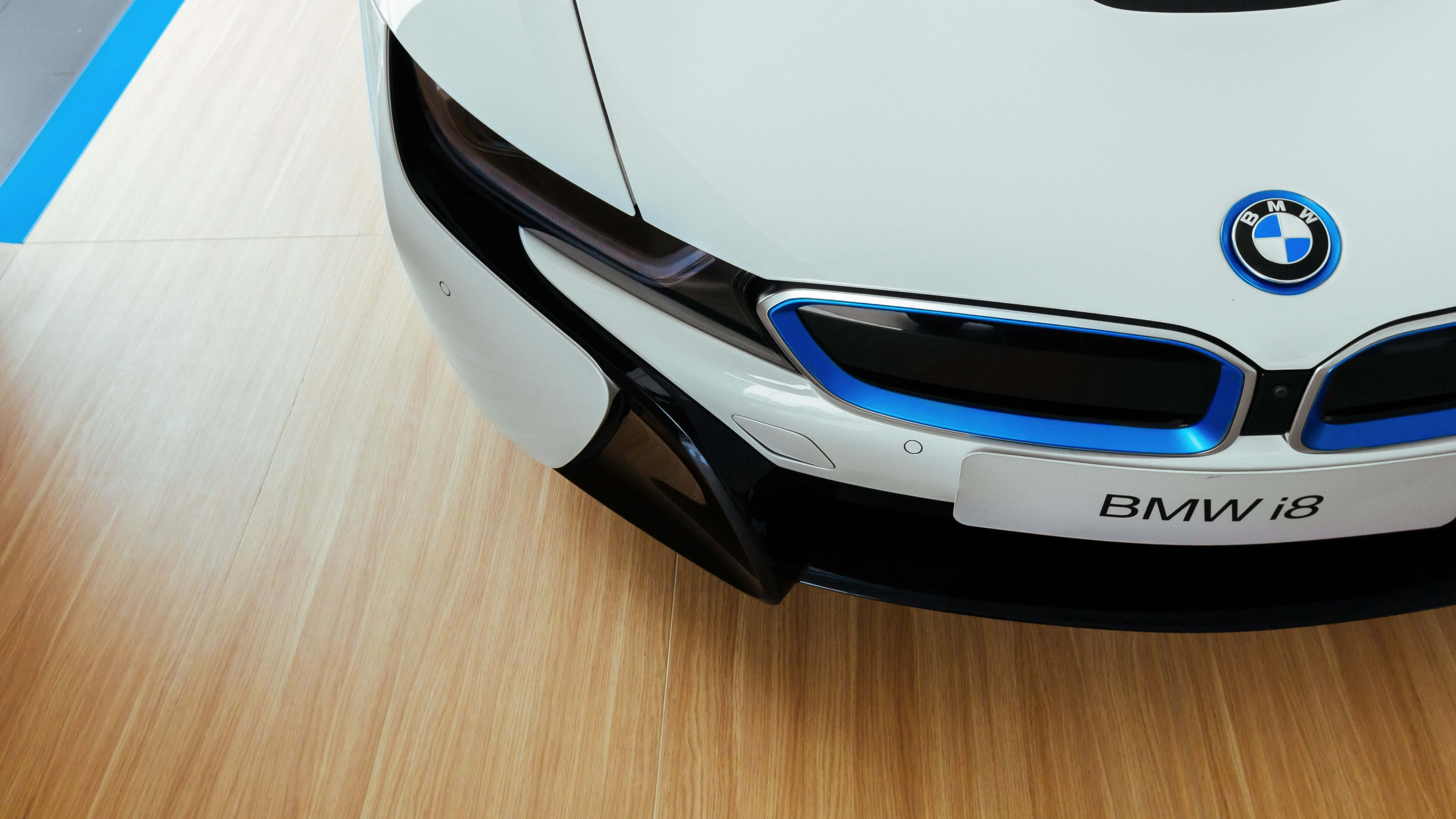 跑車 桌布 壁紙 — 白色BMW i8未來感前格柵特寫，在淺色木地板上帶有發光藍色飾邊。