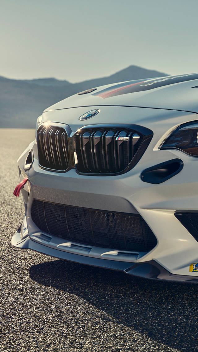 m 桌布 壁紙 — 白色BMW M2賽車的侵略性車頭在明亮的陽光下閃閃發光，背景是沙漠山脈。