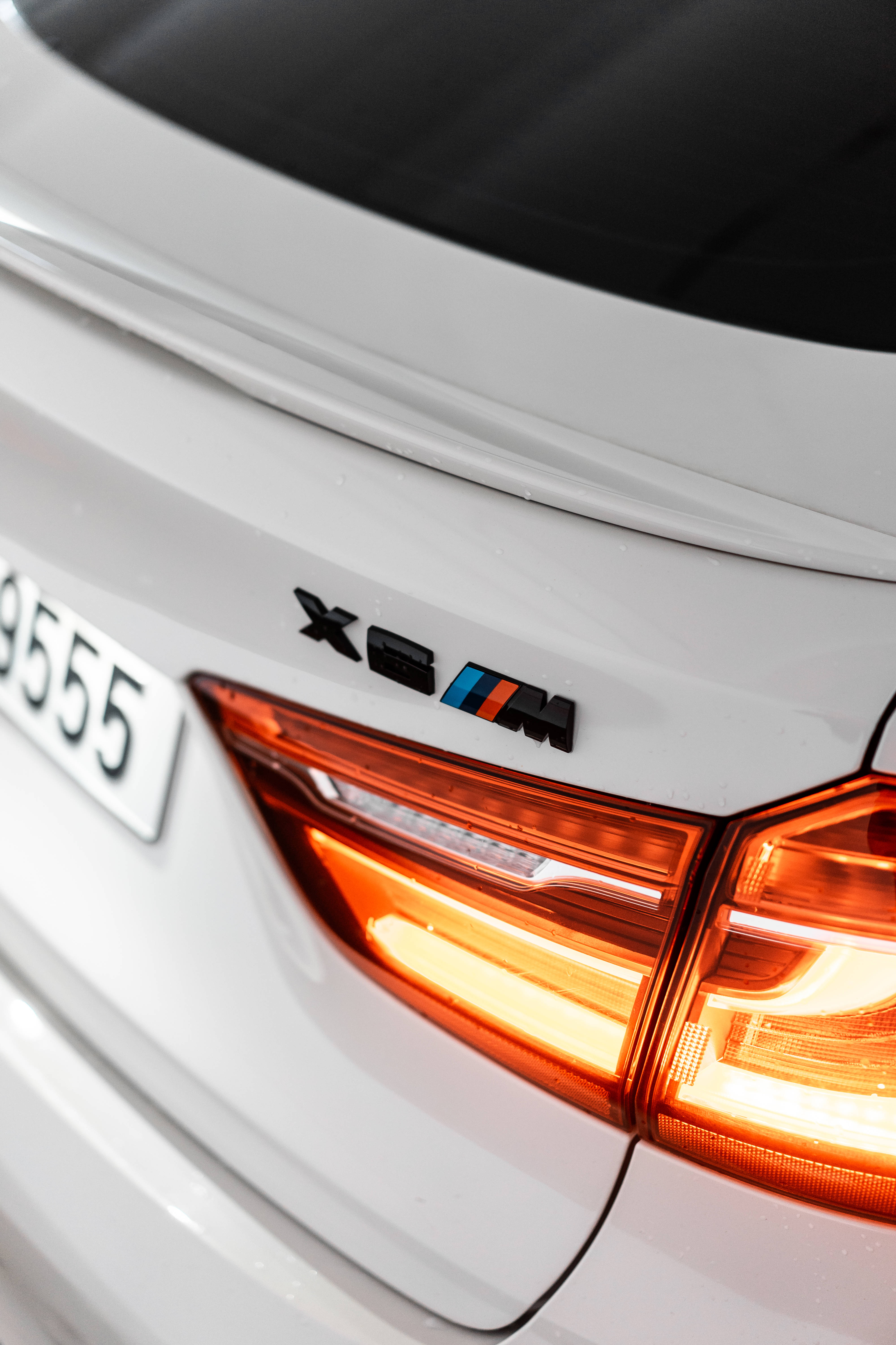 m 桌布 壁紙 — 白色BMW X6 M發光尾燈及帶有車牌9555徽章的近距離特寫。