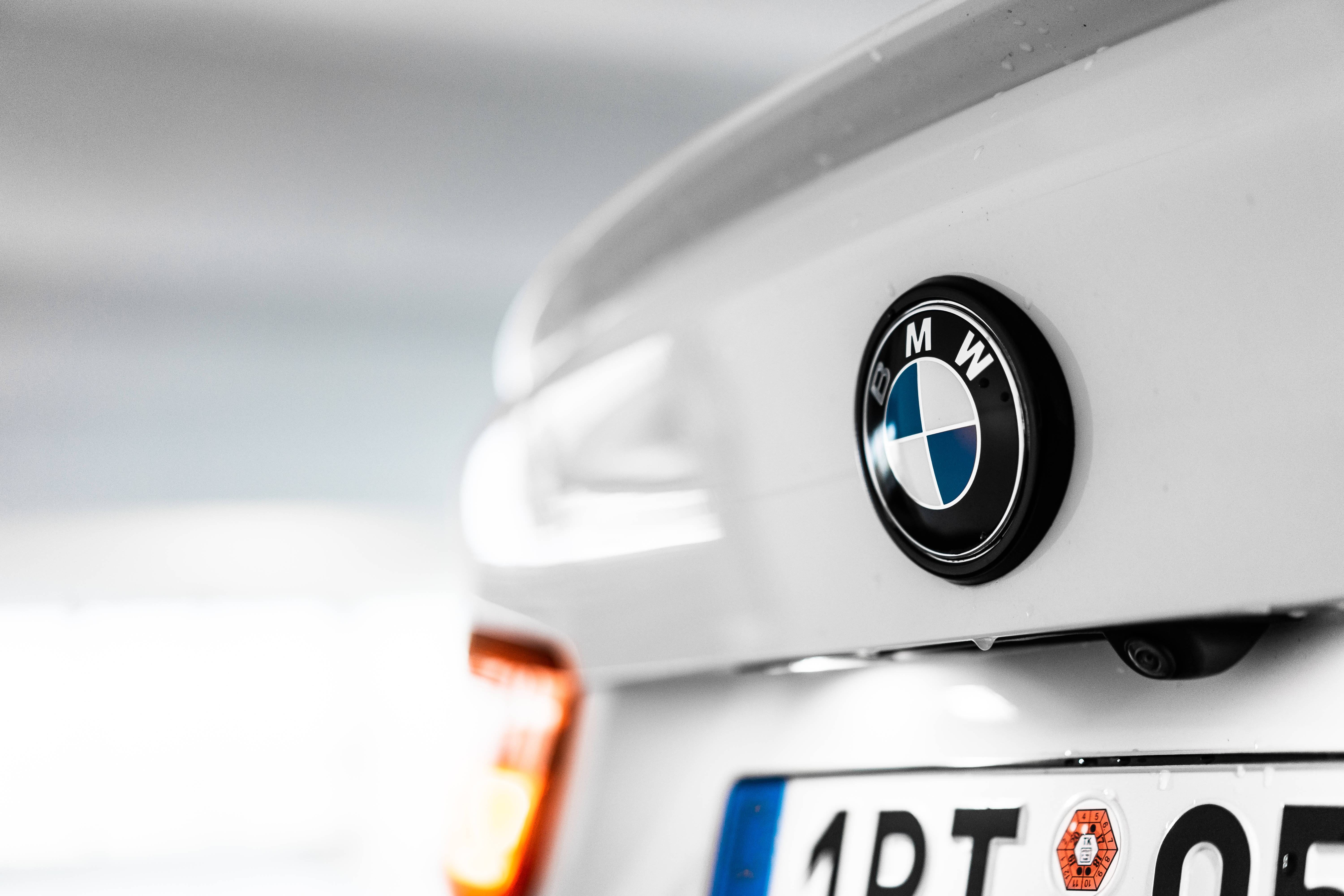 標誌 桌布 壁紙 — 白色BMW汽車後方標誌的特寫，雨滴在其光滑表面上閃閃發光。