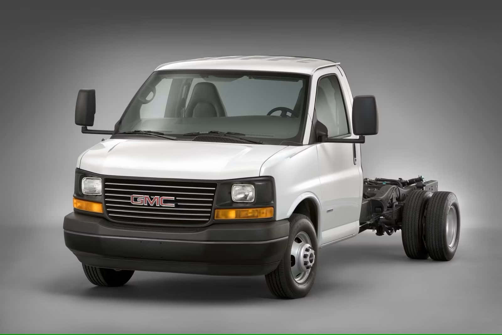 Gmc Savana 桌布 壁紙 — 白色GMC貨車底盤，後輪外露，無貨箱，立於中性灰色工作室背景前。