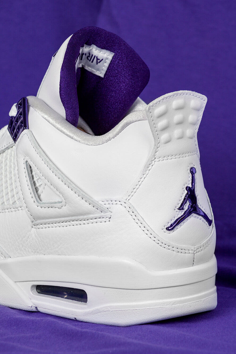 Purple Jordan 桌布 壁紙 — 白色Jordan 4運動鞋近距離特寫，帶有紫色點綴，背景為純紫色。
