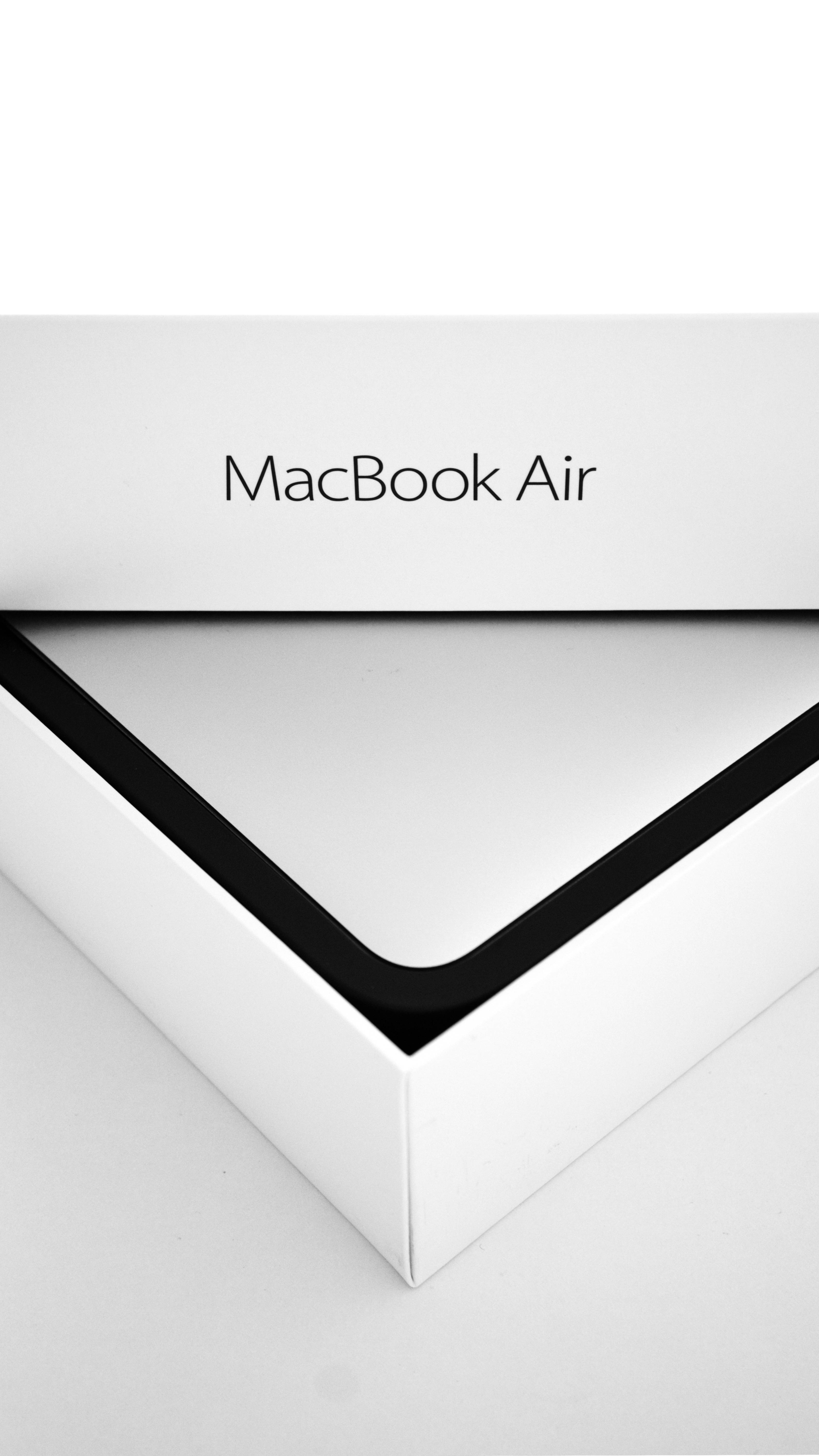 Macbook Air 2020 桌布 壁紙 — 白色MacBook Air包裝盒的特寫，黑色邊框和極簡字體設計，背景為純白色。