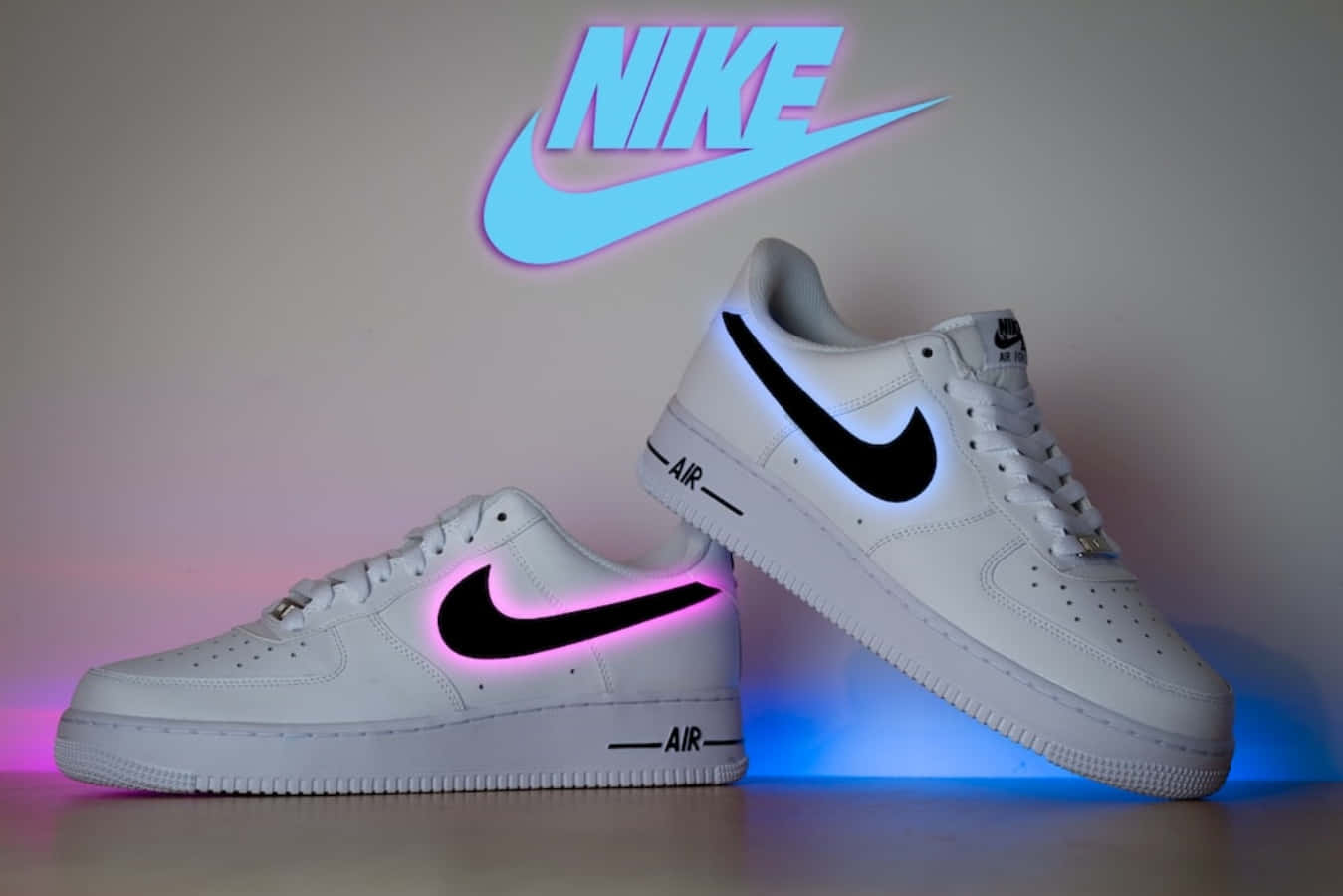 桌布 壁紙 — 白色Nike Air Force 1運動鞋在帶有發光Nike標誌的簡約牆壁襯托下，散發出充滿活力的粉紅色和藍色LED燈光。