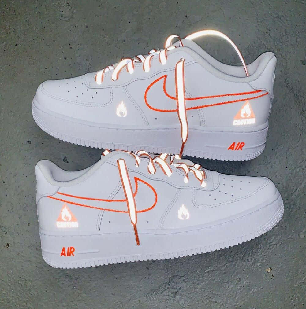 Nike Air Force 桌布 壁紙 — 白色Nike Air Force 1運動鞋，帶有橙色火焰裝飾和「CAUTION」文字，放置在紋理灰色混凝土表面上。
