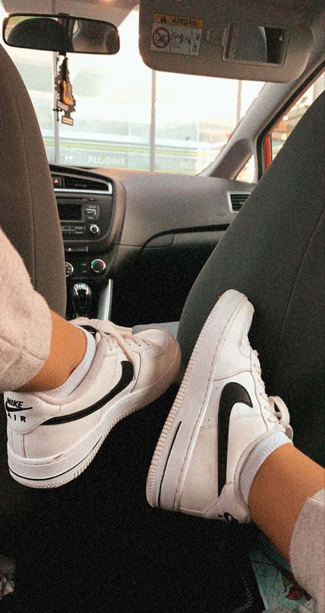Nike Air Force 桌布 壁紙 — 白色Nike Air運動鞋放在汽車座椅上，雙腳在儀表板附近晃動。