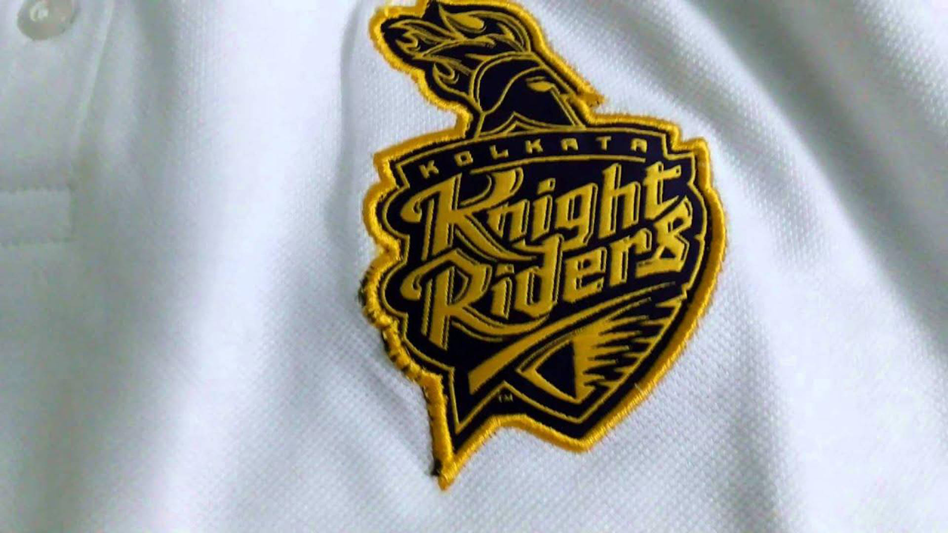 Riders 桌布 壁紙 — 白色Polo衫布料上金色和黑色刺繡的Kolkata Knight Riders標誌特寫。