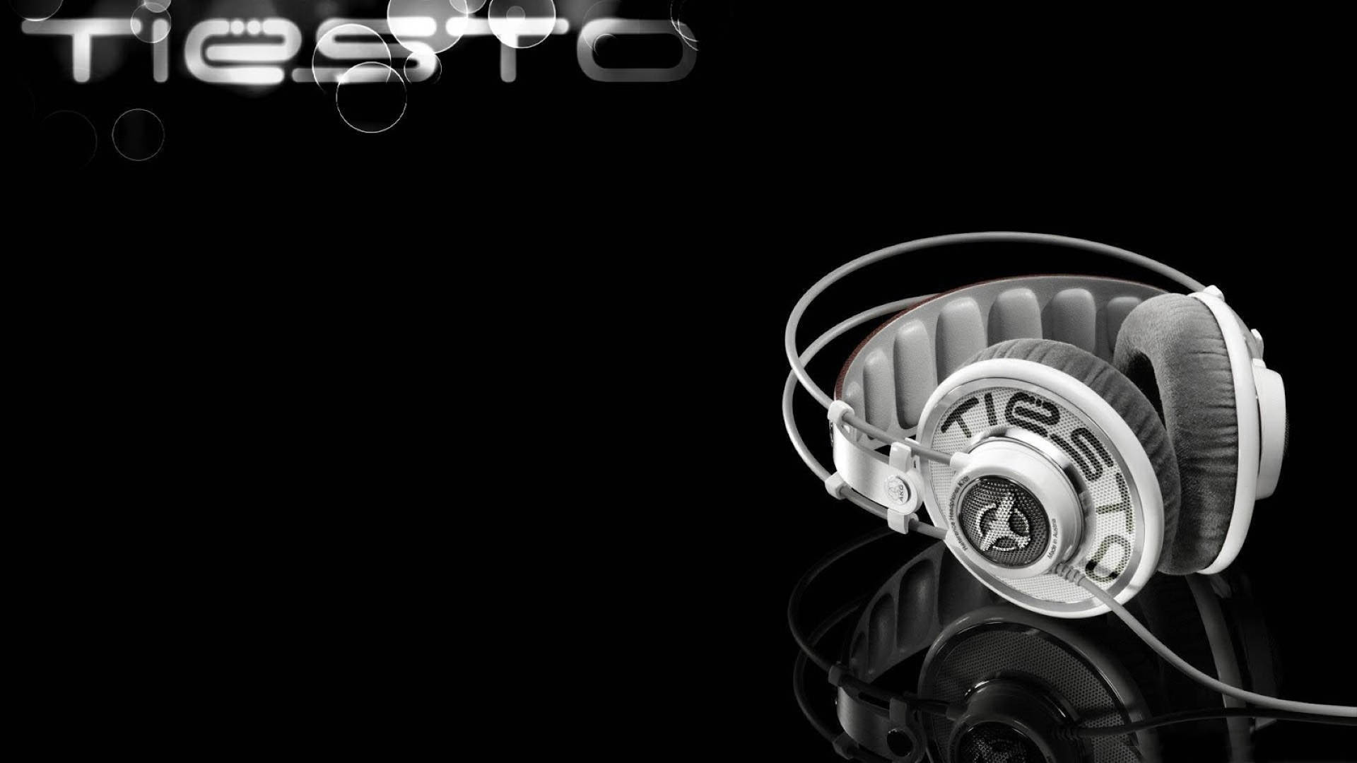 Tiesto 桌布 壁紙 — 白色Tiesto品牌耳機放置在反光的黑色表面上，黑暗背景中有發光的標誌和散景氣泡。