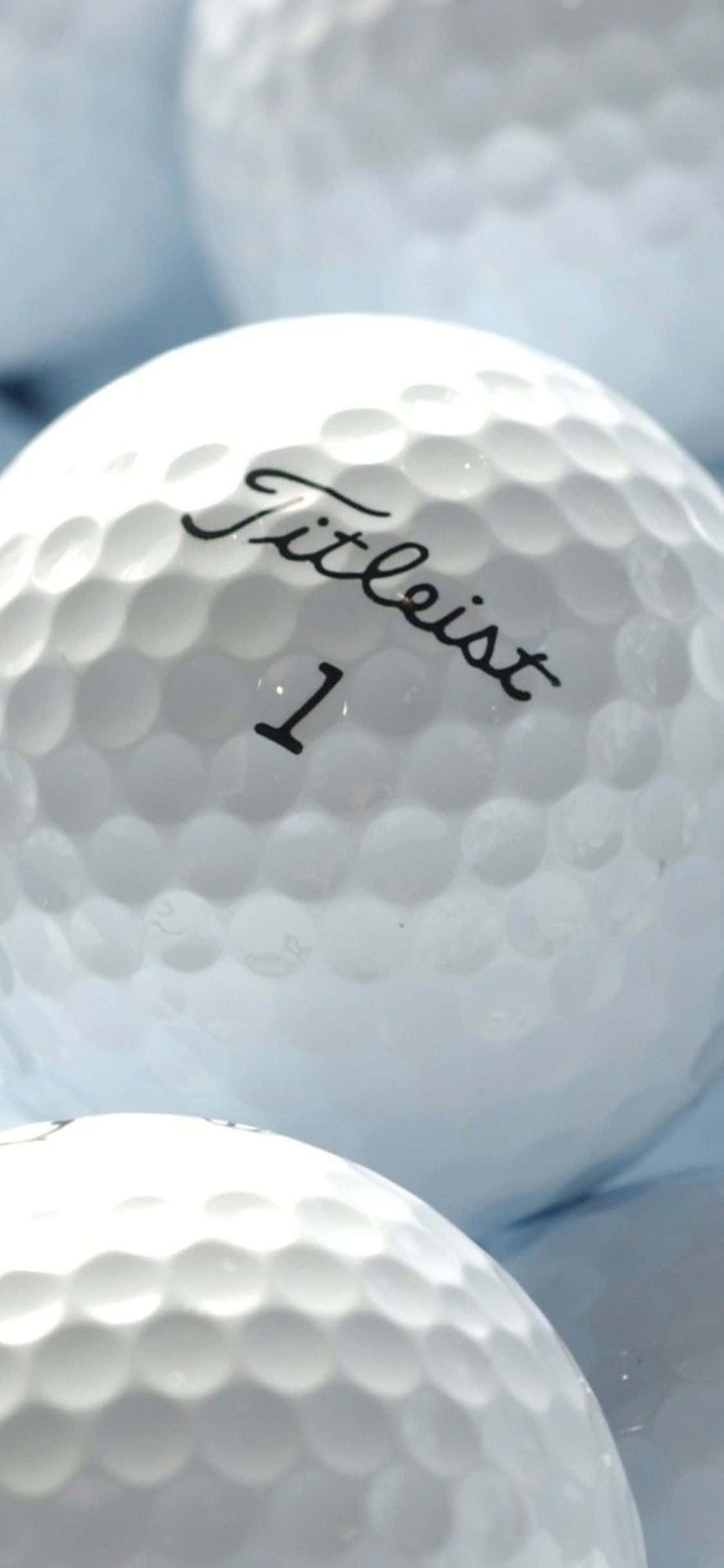 高爾夫 桌布 壁紙 — 白色Titleist高爾夫球特寫，帶有凹坑紋理和黑色標誌，背景柔和。