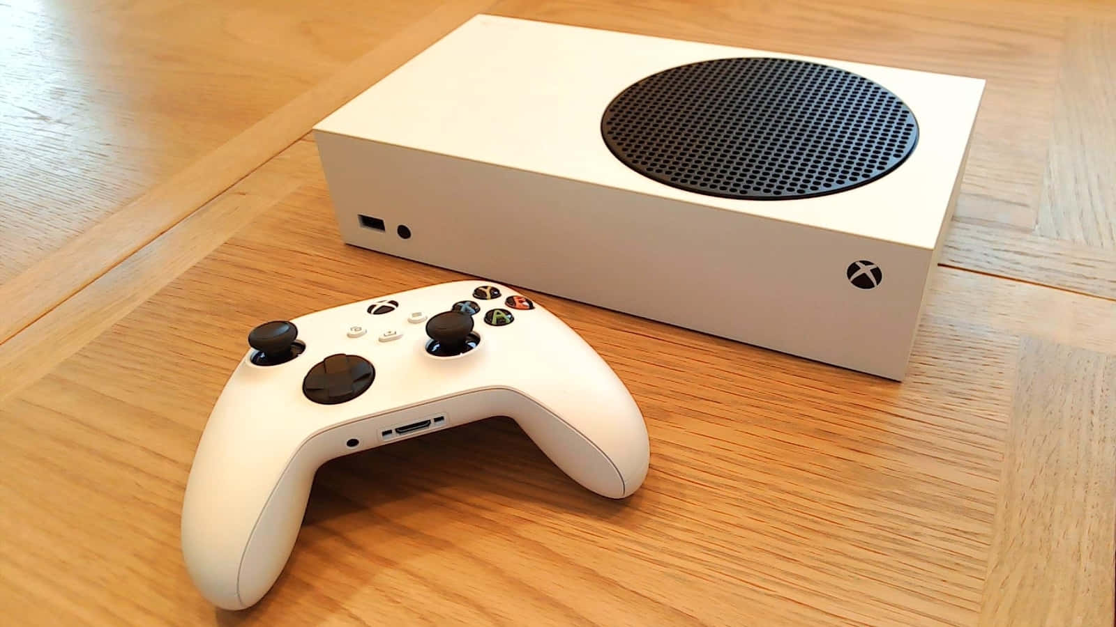 Xbox 桌布 壁紙 — 白色Xbox主機及手把放在淺色木地板上，帶有天然木紋質感。