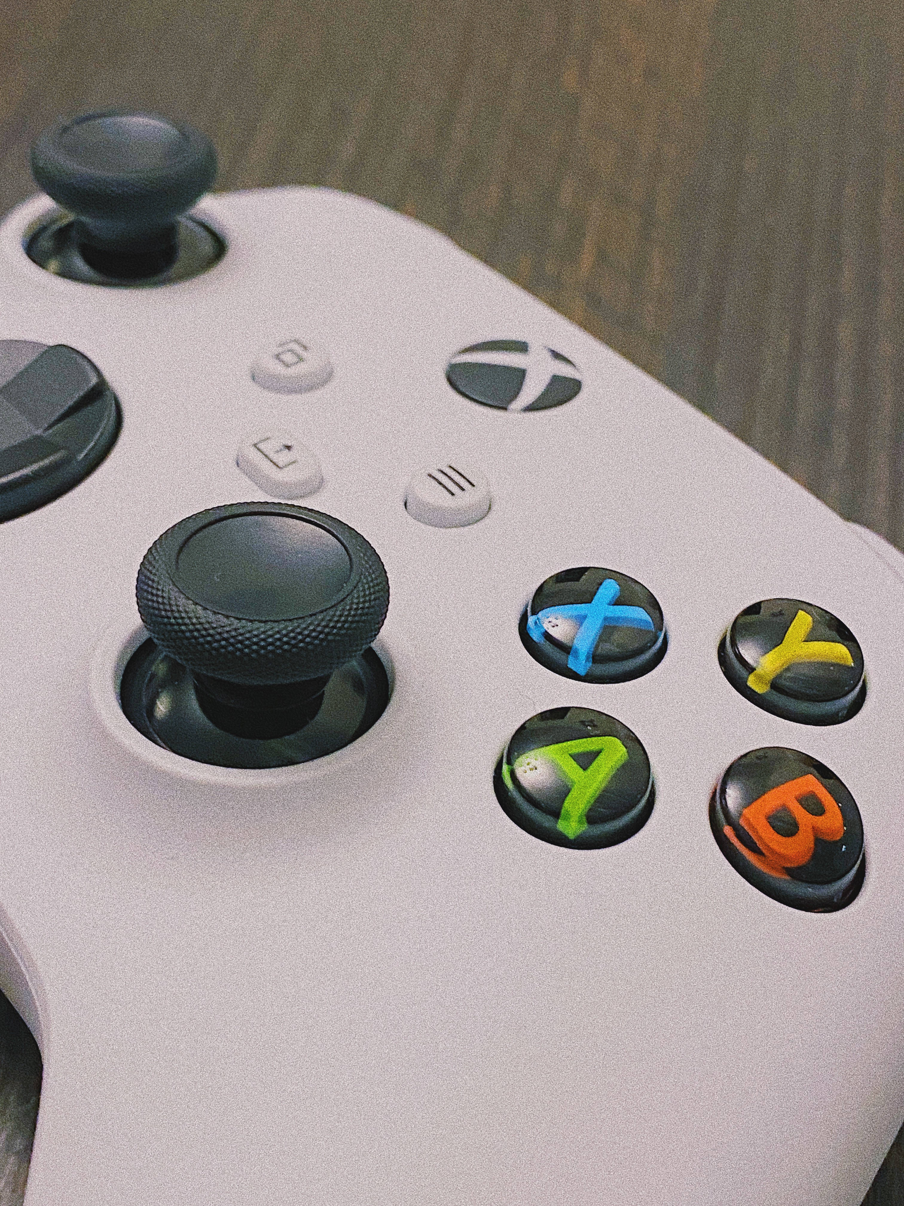 Joystick 桌布 壁紙 — 白色Xbox手把特寫，帶有彩色ABXY按鈕，放置在木質表面上。