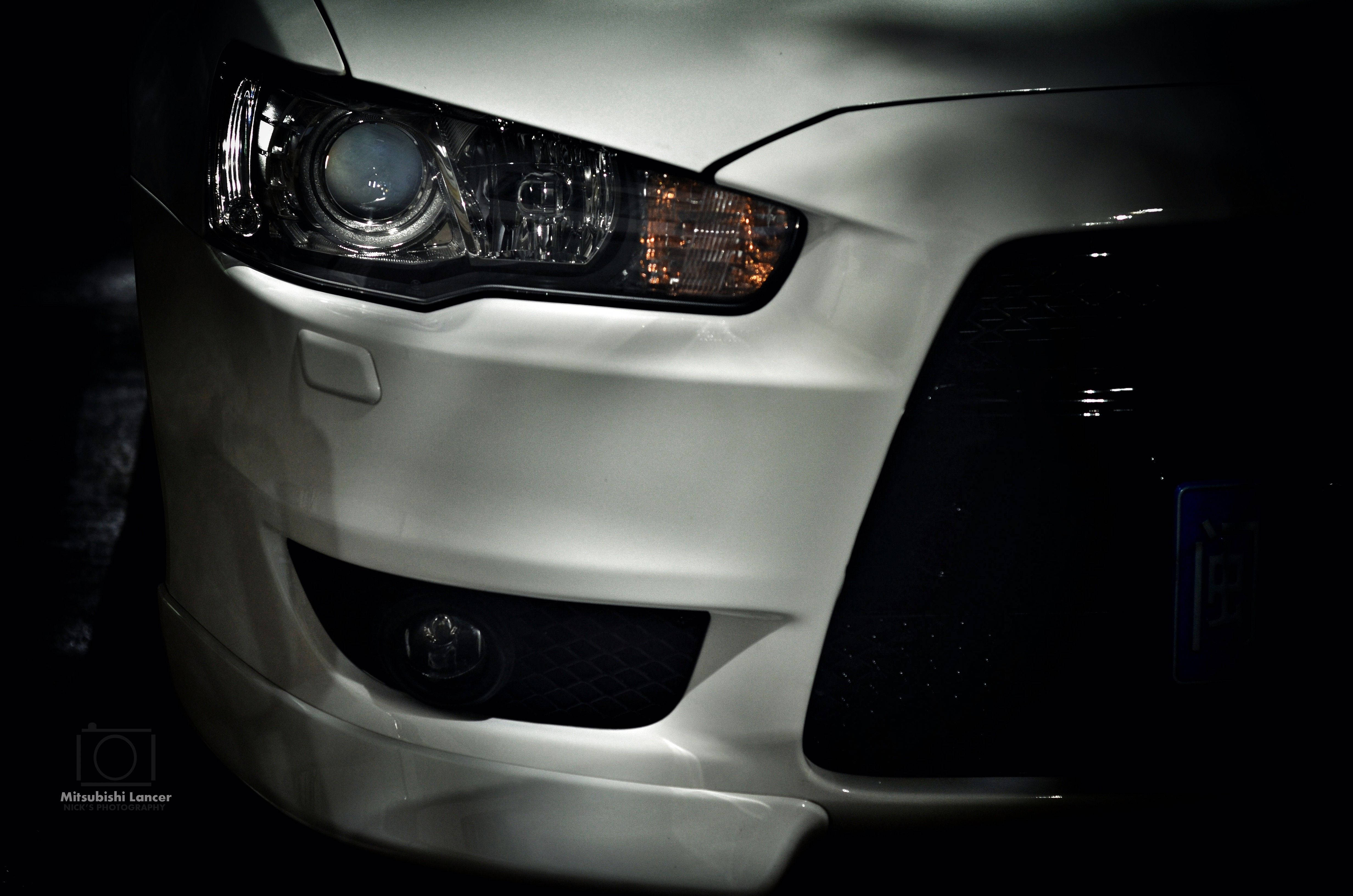 Mitsubishi 桌布 壁紙 — 白色三菱Lancer車頭的特寫，在黑暗背景下以戲劇性的低調照明照亮。