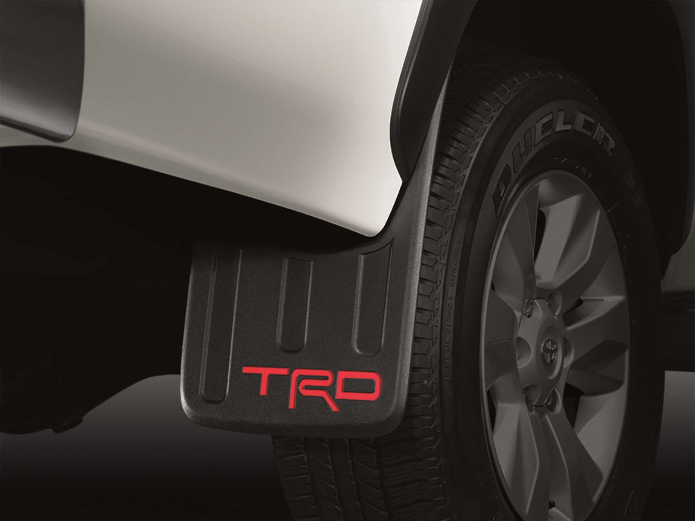 Toyota 桌布 壁紙 — 白色卡車的黑色TRD擋泥板特寫，帶有紅色字樣，旁邊是堅固的輪胎。