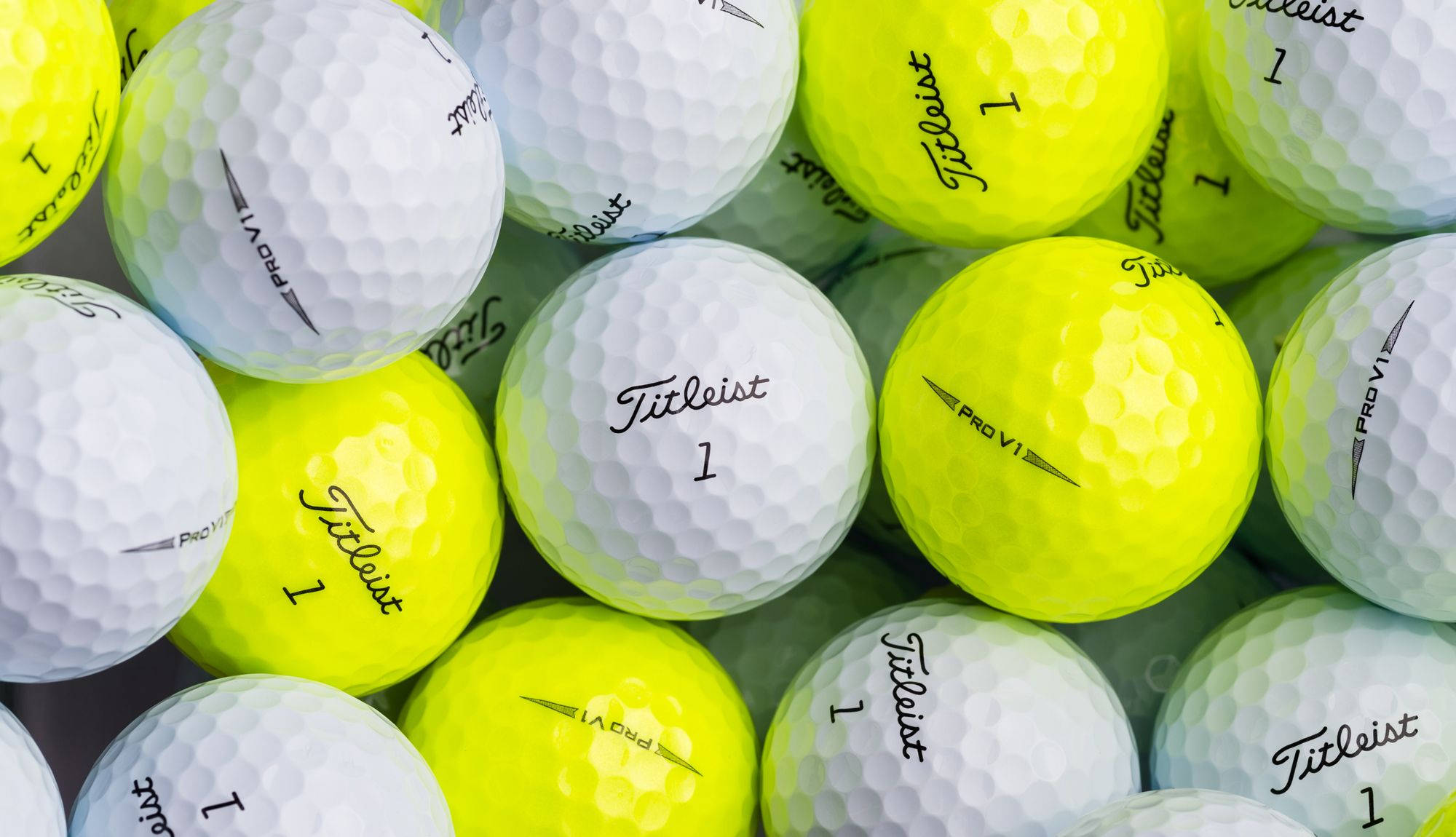 Golfing 桌布 壁紙 — 白色和亮黃色 Titleist 高爾夫球的特寫，可見凹痕和品牌標誌。