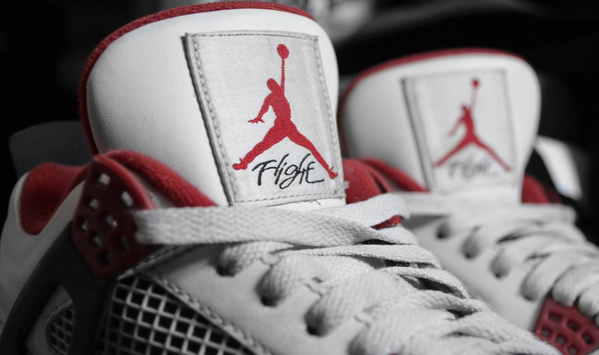 Jordan球鞋 桌布 壁紙 — 白色和紅色 Air Jordan 運動鞋的特寫，標誌性的 Jumpman 標誌在模糊背景下清晰對焦。
