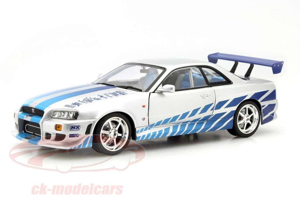 Paul Walker Skyline 桌布 壁紙 — 白色和藍色的日產Skyline GT-R模型車，帶有賽車貼紙和大型後翼，置於潔淨的白色工作室背景上。