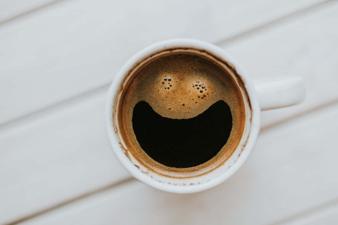 Coffee Cup 桌布 壁紙 — 白色咖啡杯頂視圖，杯上泡沫形成笑臉，置於淺色木質表面。